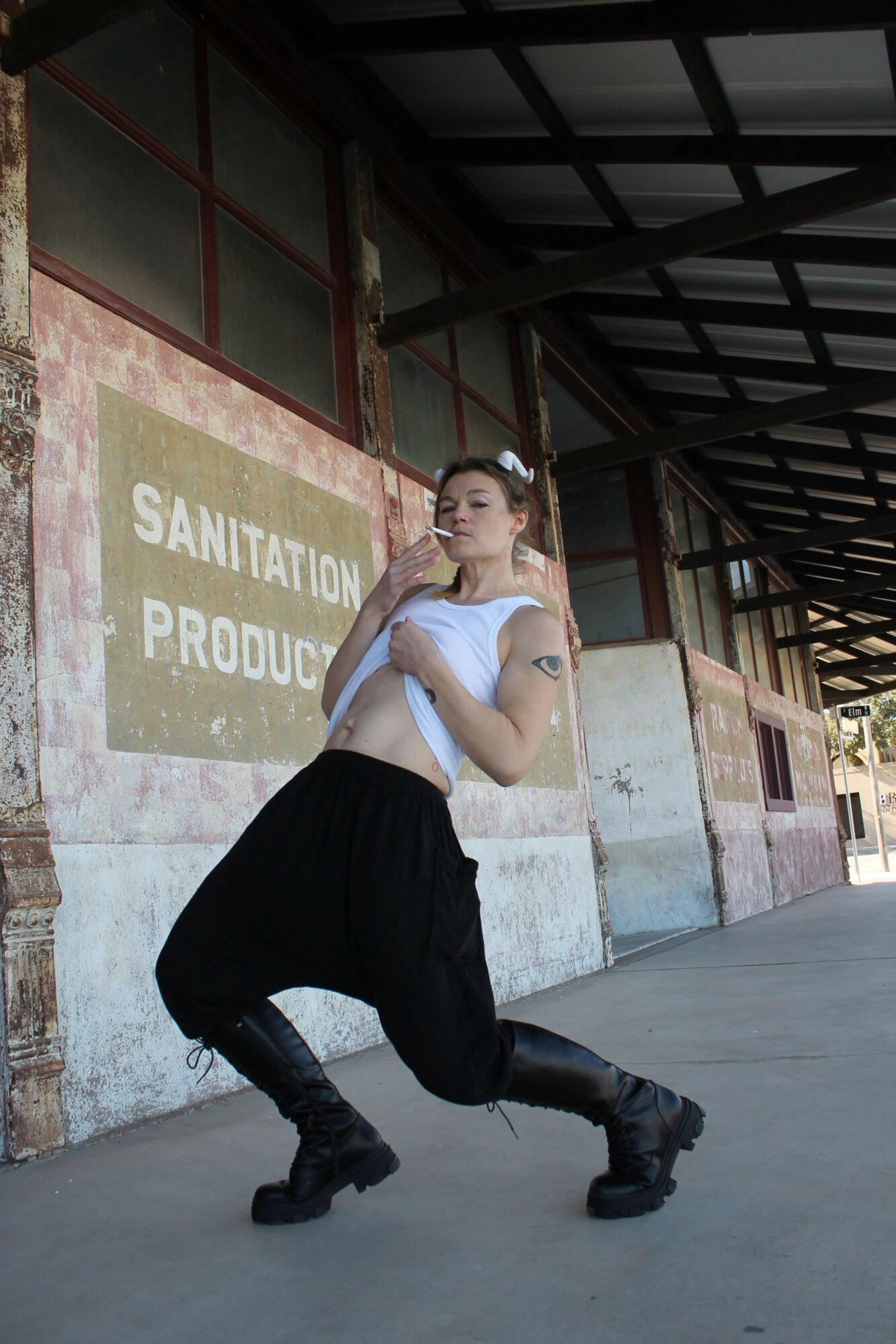 Woman sitting on a concrete block, talking on a cellphone, with a sign and building in the background.