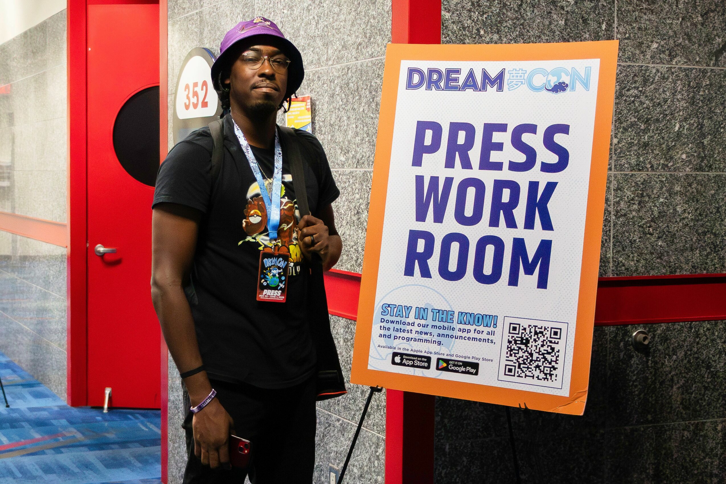 Person standing next to a sign that reads 'Press Work Room' at a conference or event.