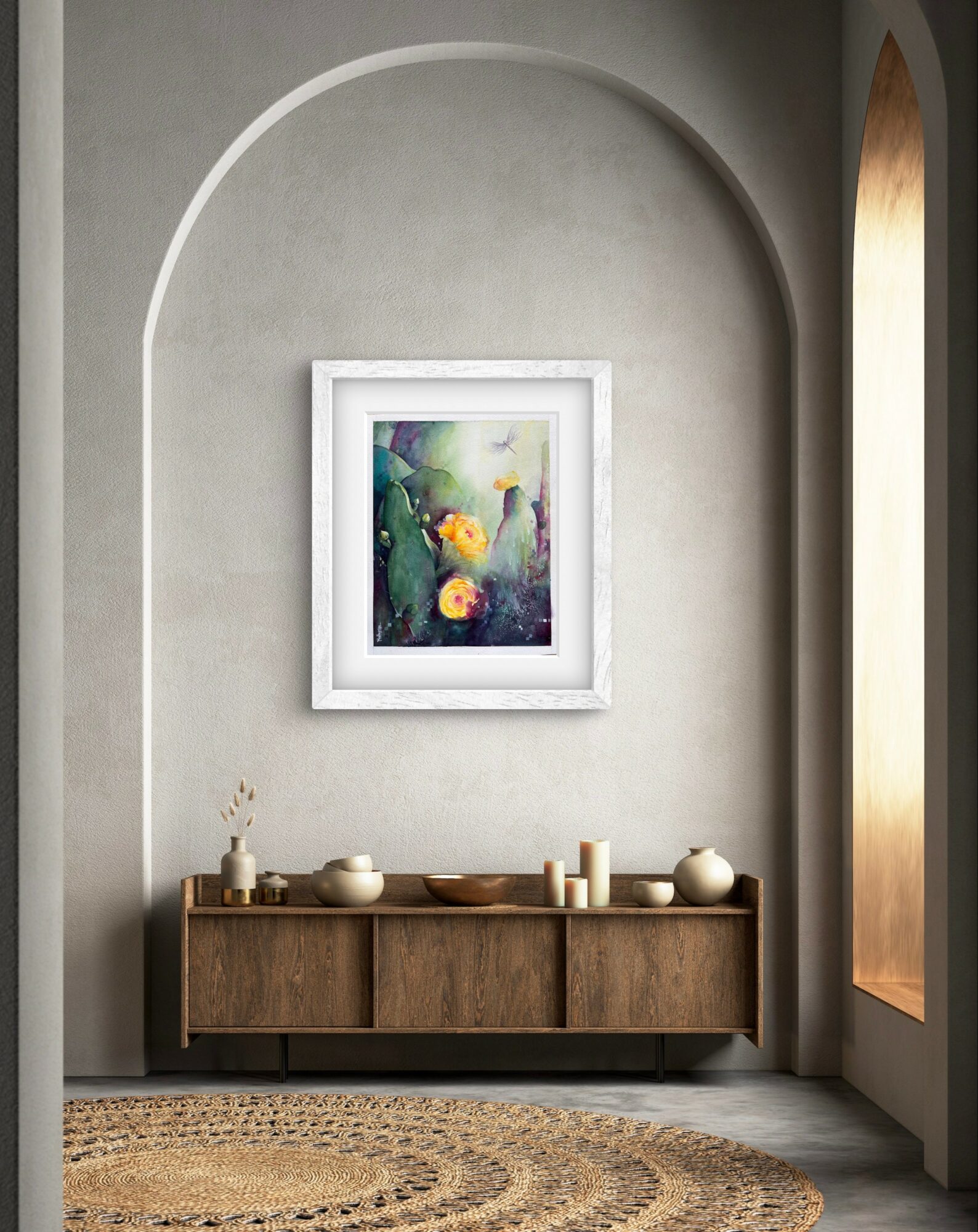 A framed colorful abstract painting hangs above a wooden sideboard in a room with arched wall and window, beige walls, and a patterned rug.