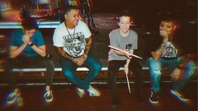 Four people sitting on a bench at night, two holding books, smiling and talking.