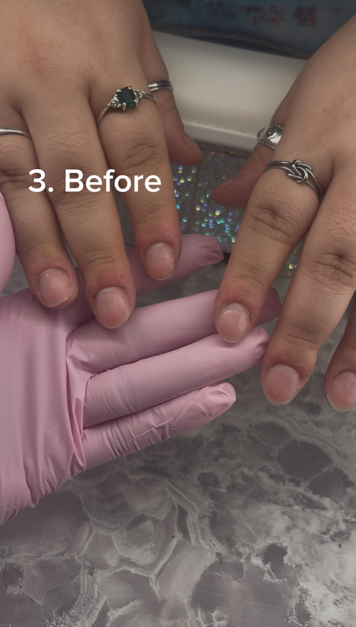 Two hands with rings touch a pink glove on a gray surface, with text '3. Before' overlayed.