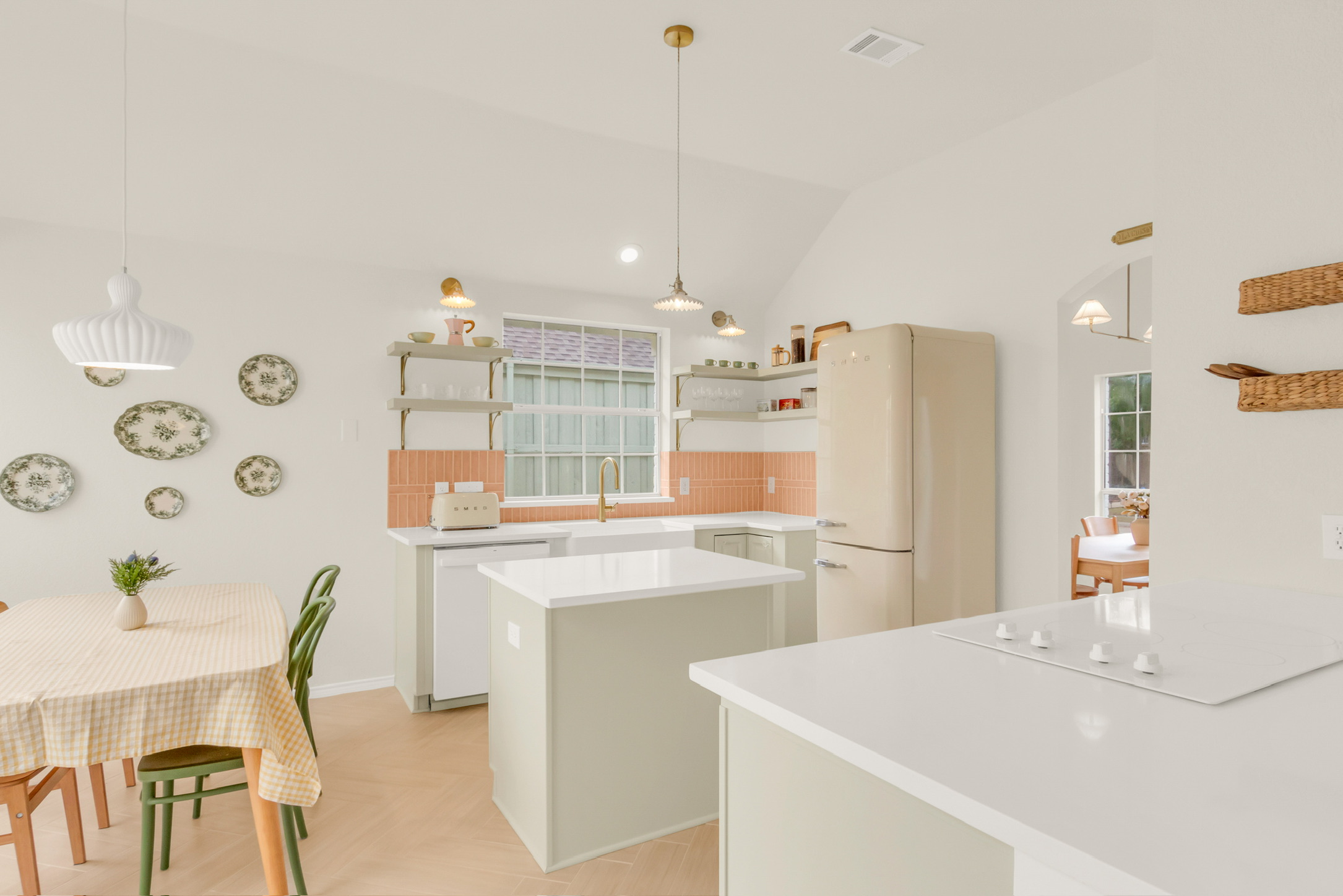 Kitchen with white cabinets, a central island, a refrigerator, and a window above the sink, with a dining area nearby.