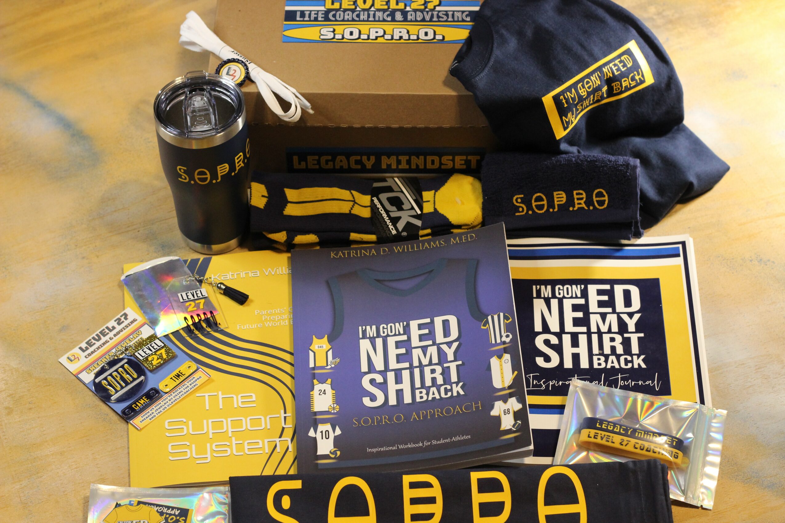 Collection of S.E.P.R.O. merchandise including a mug, hat, wristband, T-shirt, and stickers on a wooden surface.