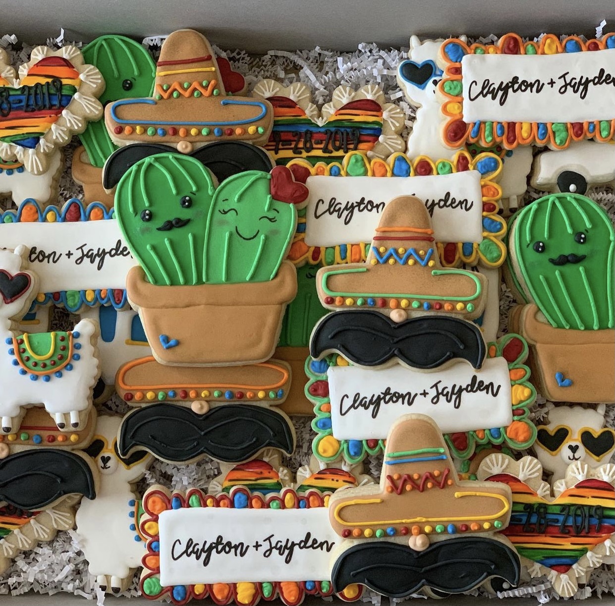 Decorated cookies with cactus, sombrero, and text reading 'Clayton + Jayden', colorful and festive, arranged on a tray.