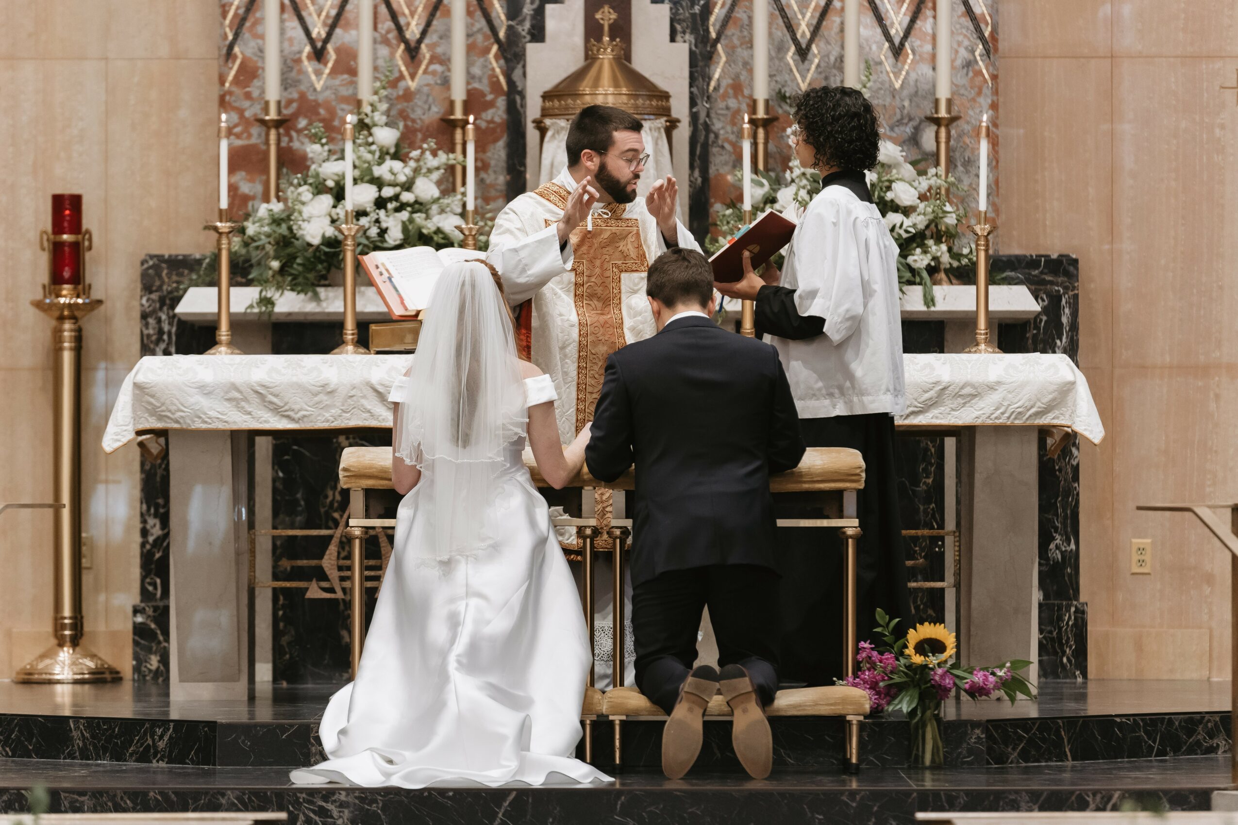 A wedding ceremony with a bride, groom, and officiant at an altar inside a church.