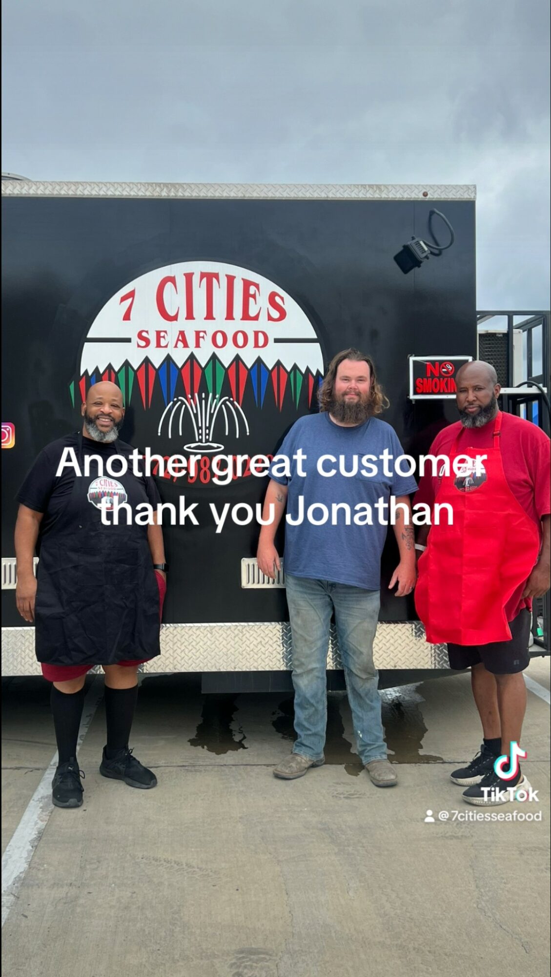 Four people stand in front of a food truck with a sign reading 