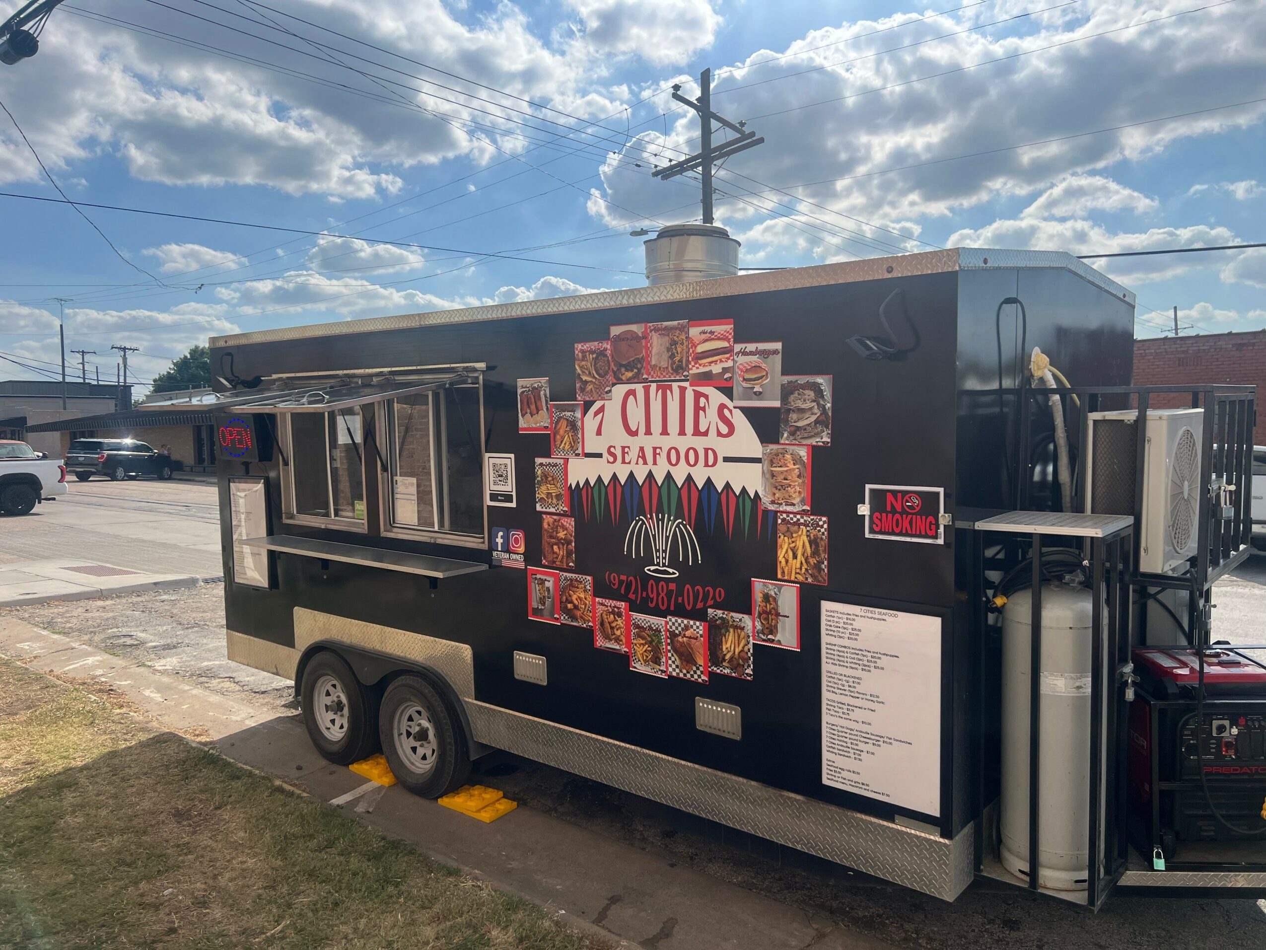 Food truck with a sign reading 'Cities Seafood' parked on the street under a partly cloudy sky.