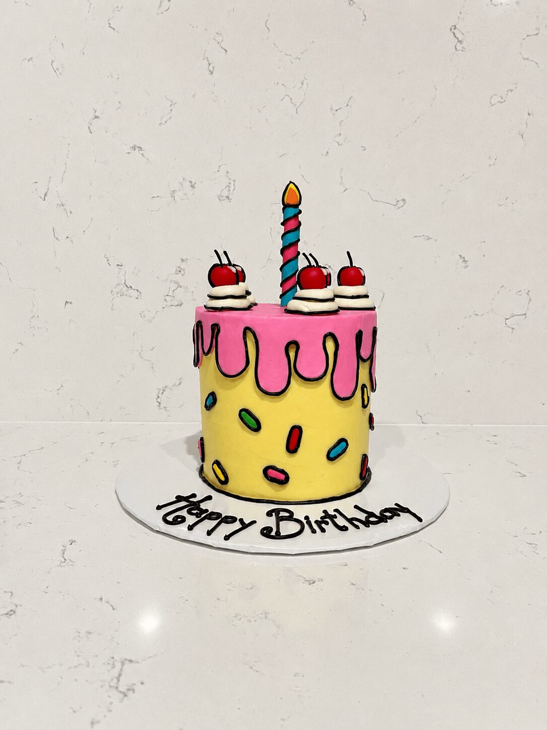 Colorful birthday cake with a single candle, pink icing, and a white base with sprinkles, on a white surface.