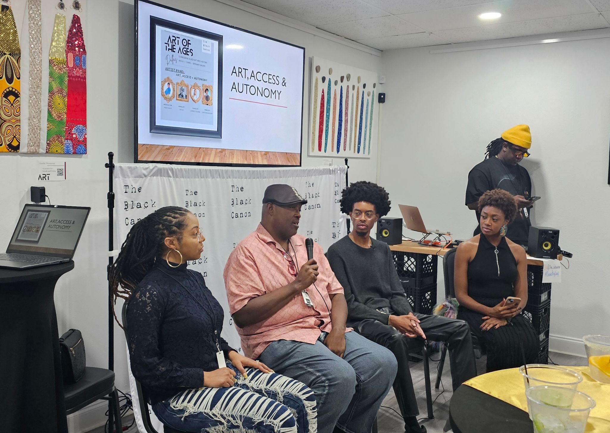 Four people seated in a panel discussion, with a whiteboard and a screen displaying 'Art Access & Autonomy' behind them.