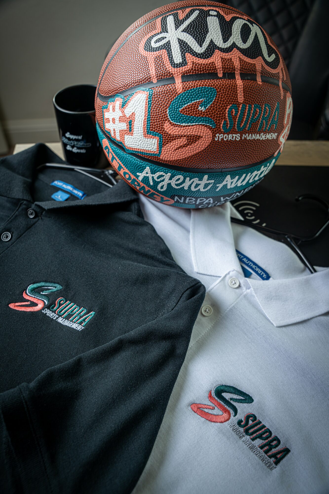 Basketball with logos resting on black and white shirts, one black and one white, with logos visible.