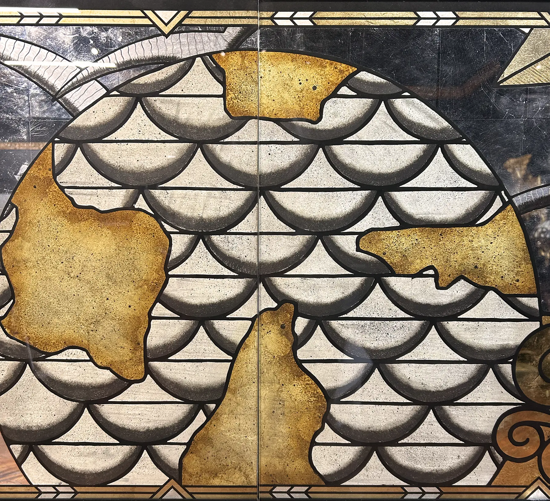 Broken pieces of a map or artwork with a fish scale pattern background, some pieces missing or damaged.