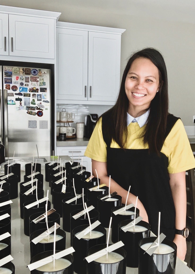 Smiling woman in yellow shirt and black apron standing in a kitchen with cupcakes on a tray.