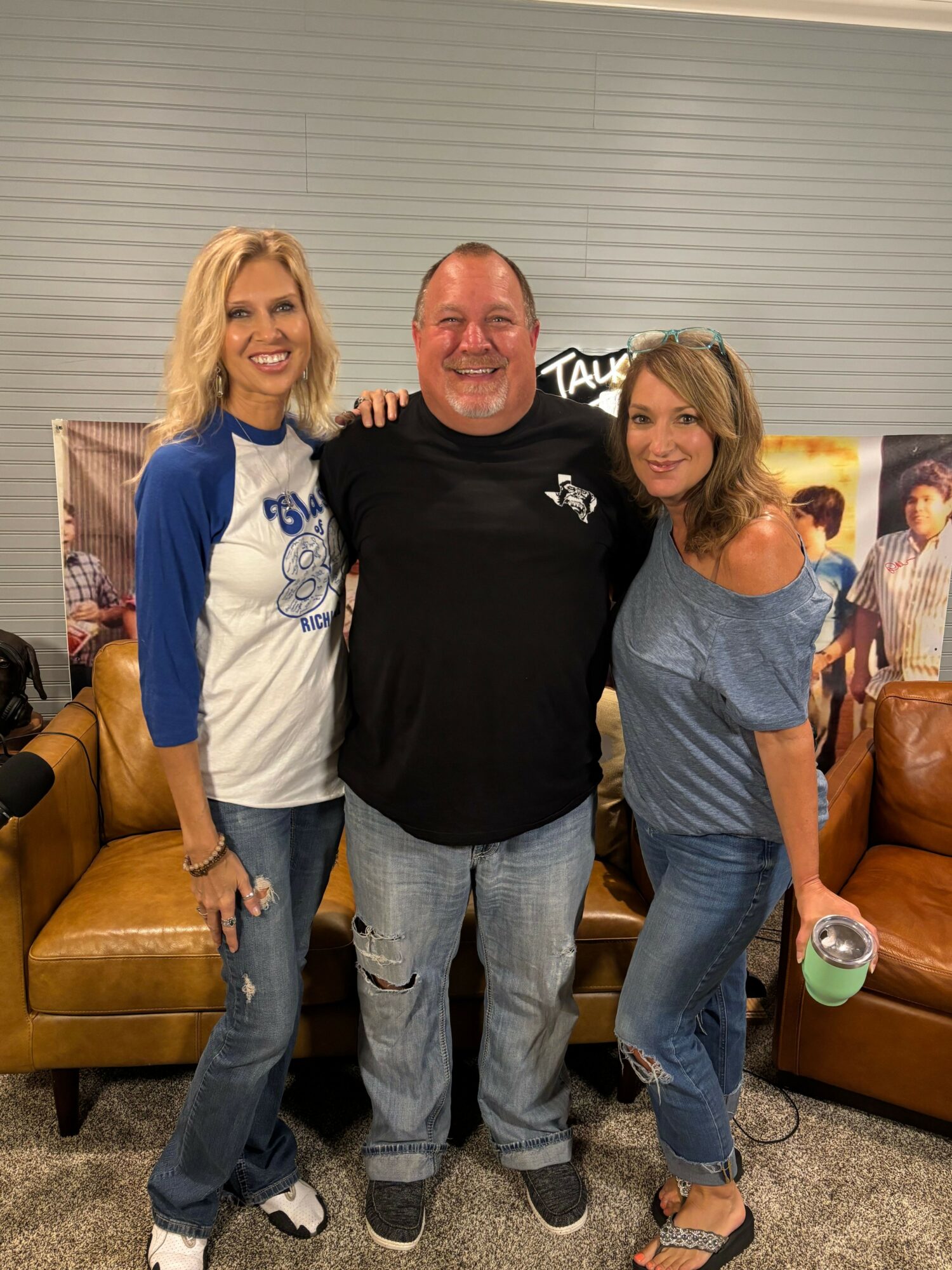 Three people standing together indoors, two women and one man, smiling and posing for the photo.