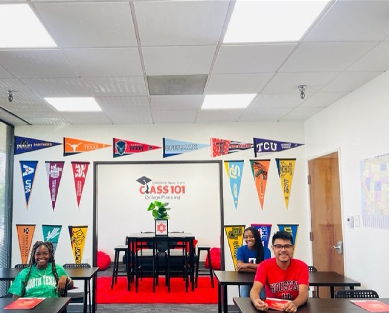 Classroom with students sitting at desks, a whiteboard with a presentation, and colorful banners on the wall.