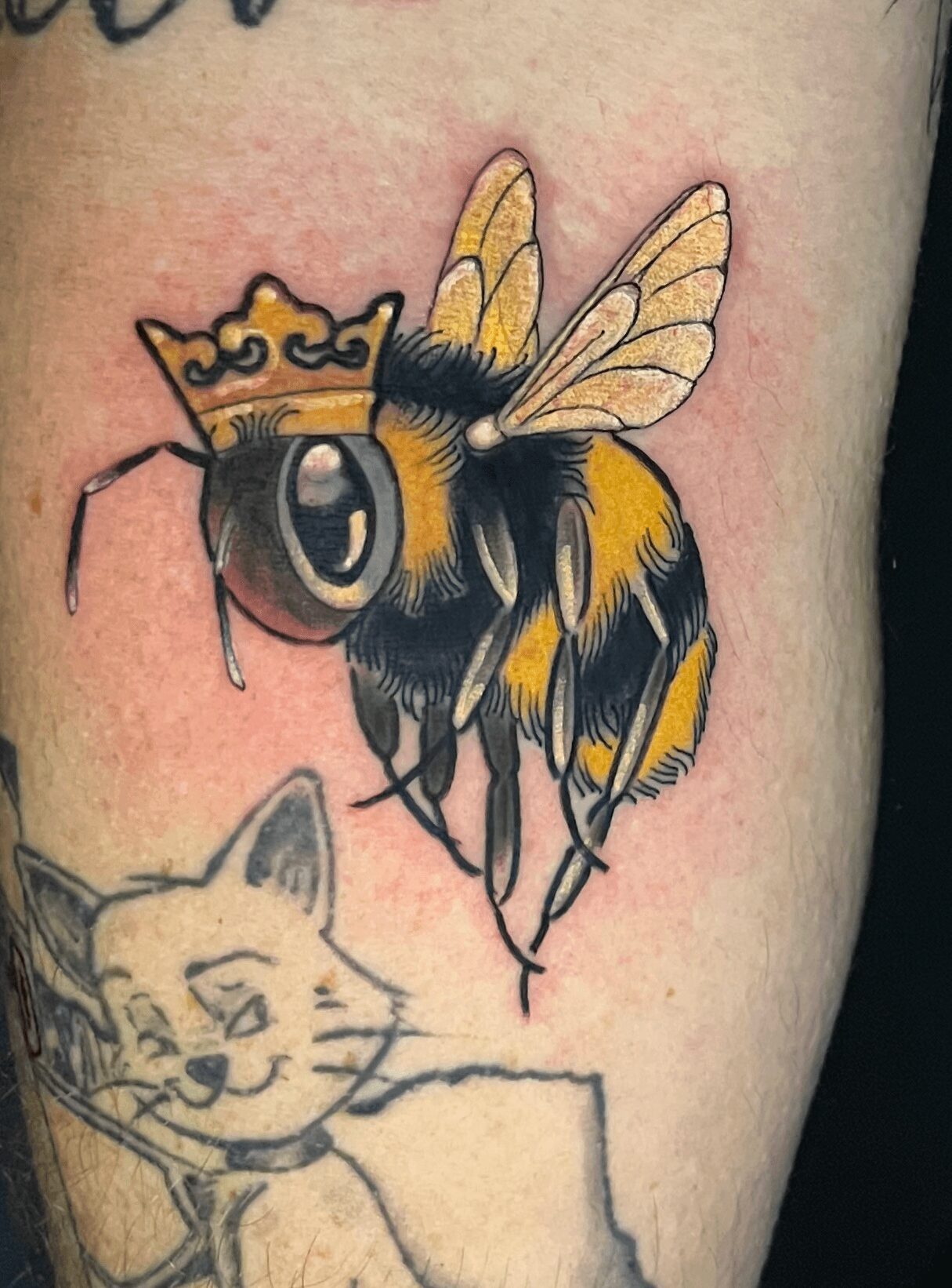 Colorful bee tattoo with wings, black and yellow body, and large eyes on skin.