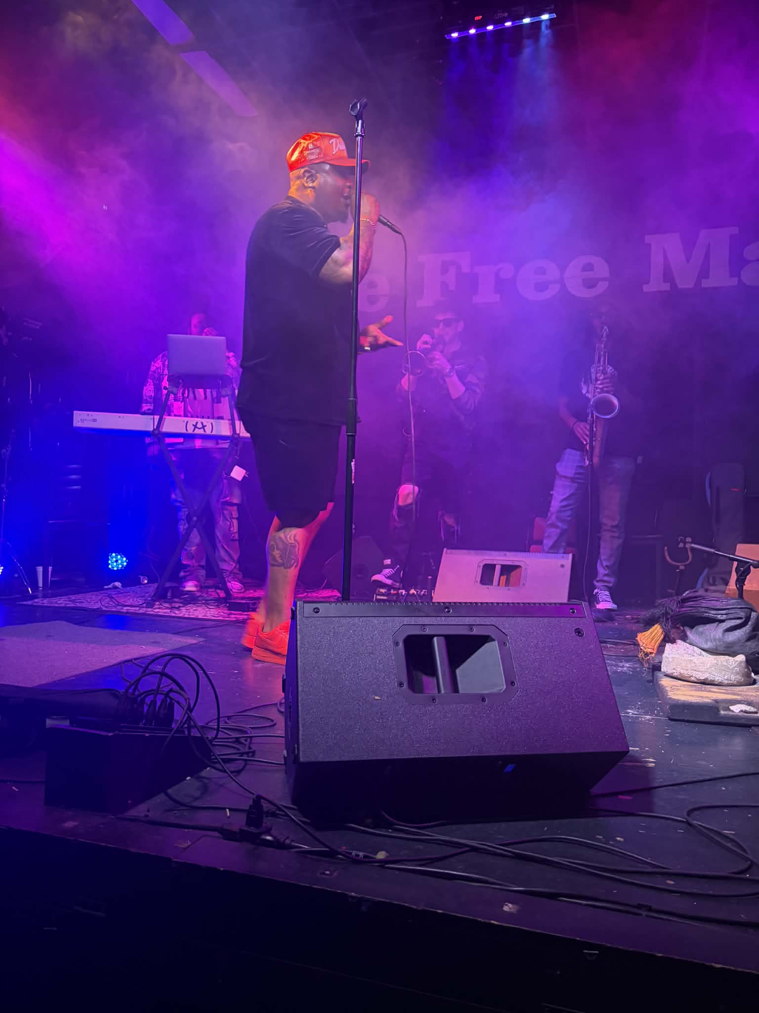 Performer with red hair and black clothing singing into a microphone on stage with purple lighting.
