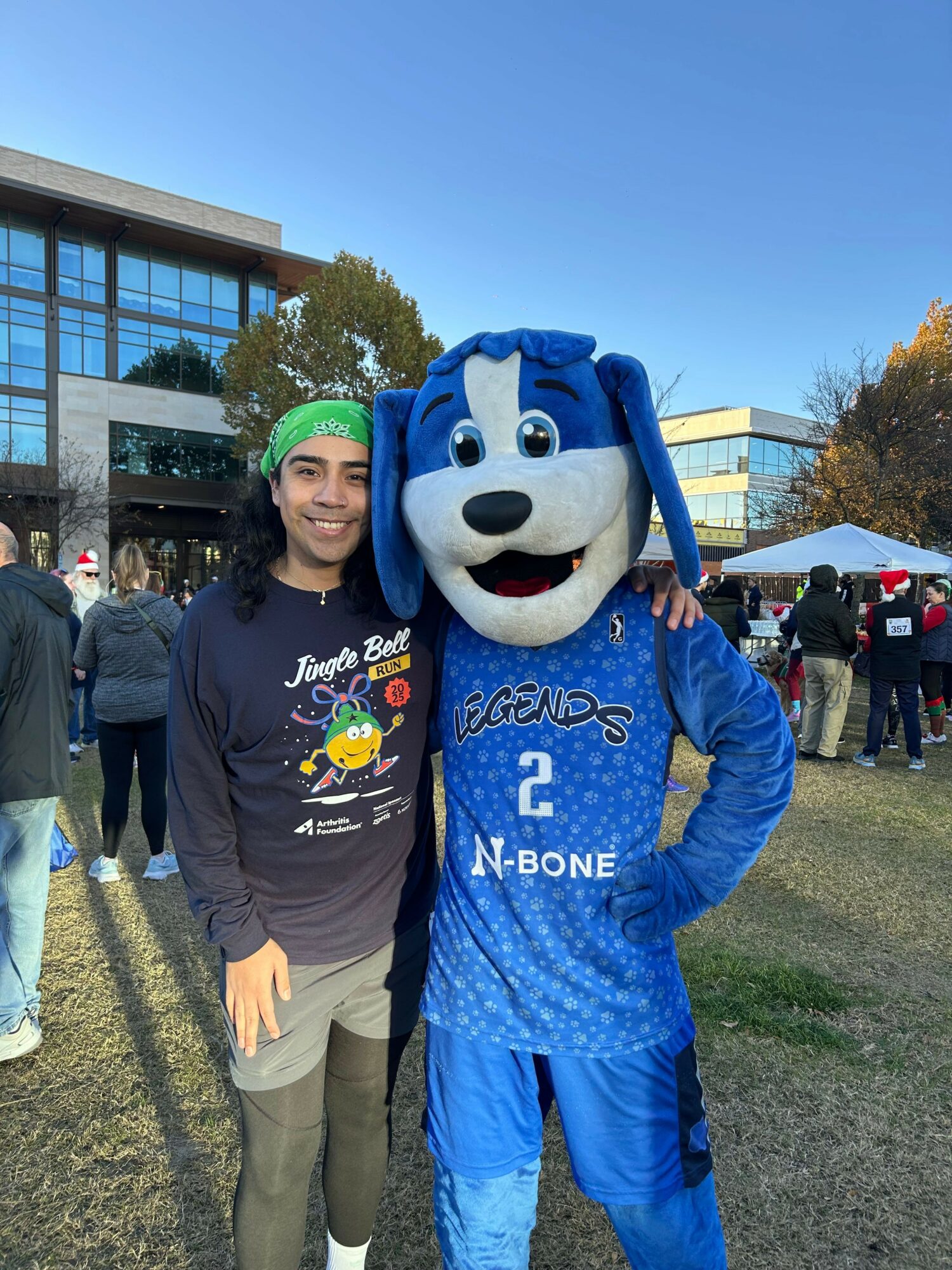 Person in mascot costume with a large white face and blue outfit standing next to a woman outdoors, both smiling.