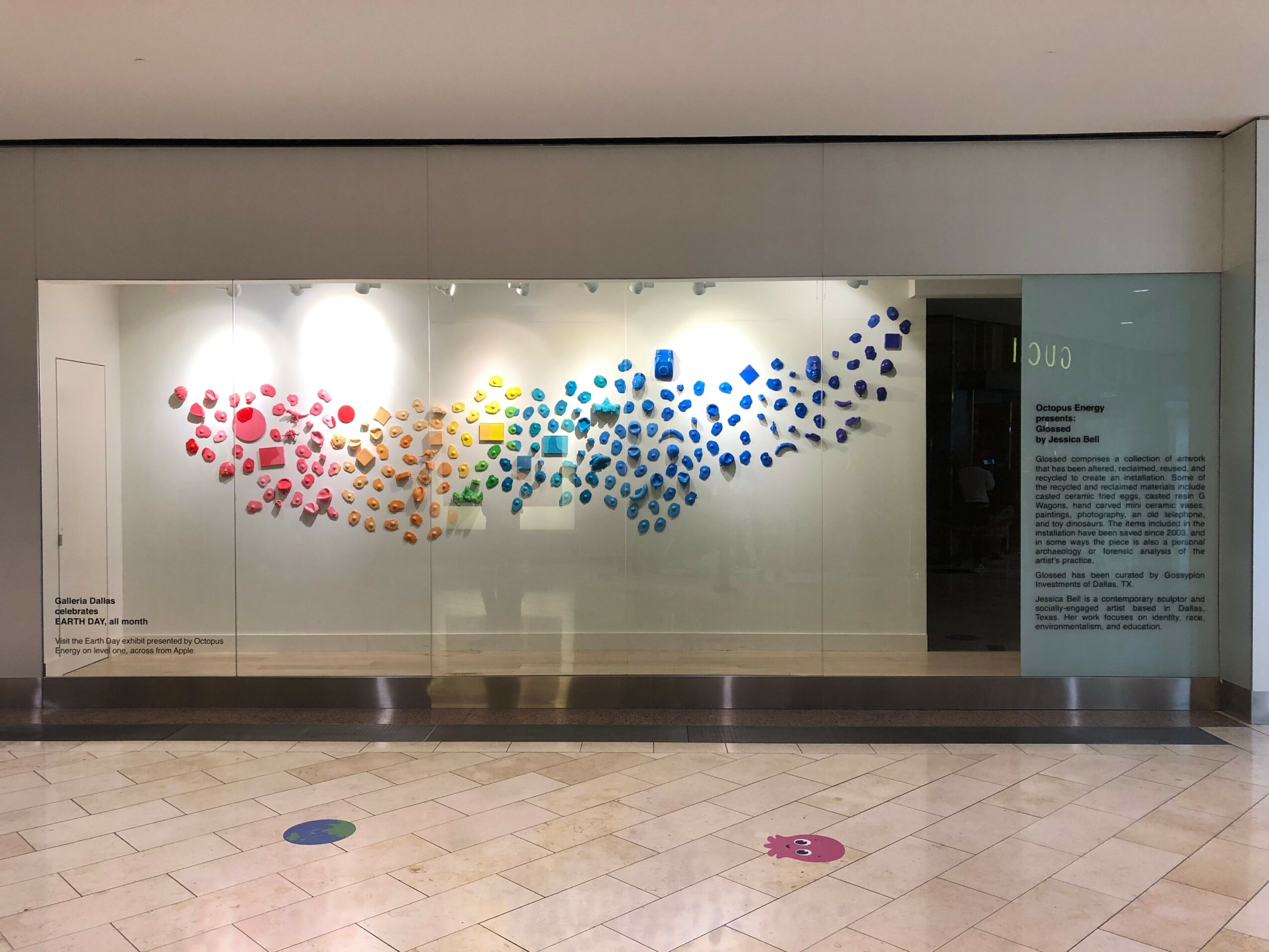 Colorful dots arranged in a wave pattern on a glass display, with informational text on the right side.