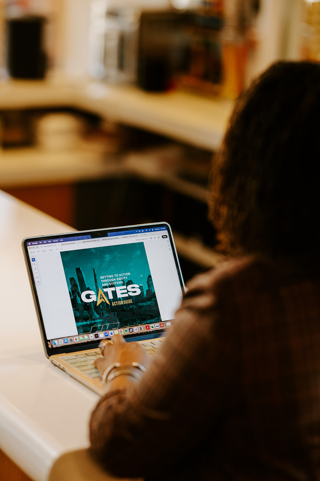 Person using a laptop with a screen displaying the name 'GATES' in a room with shelves.