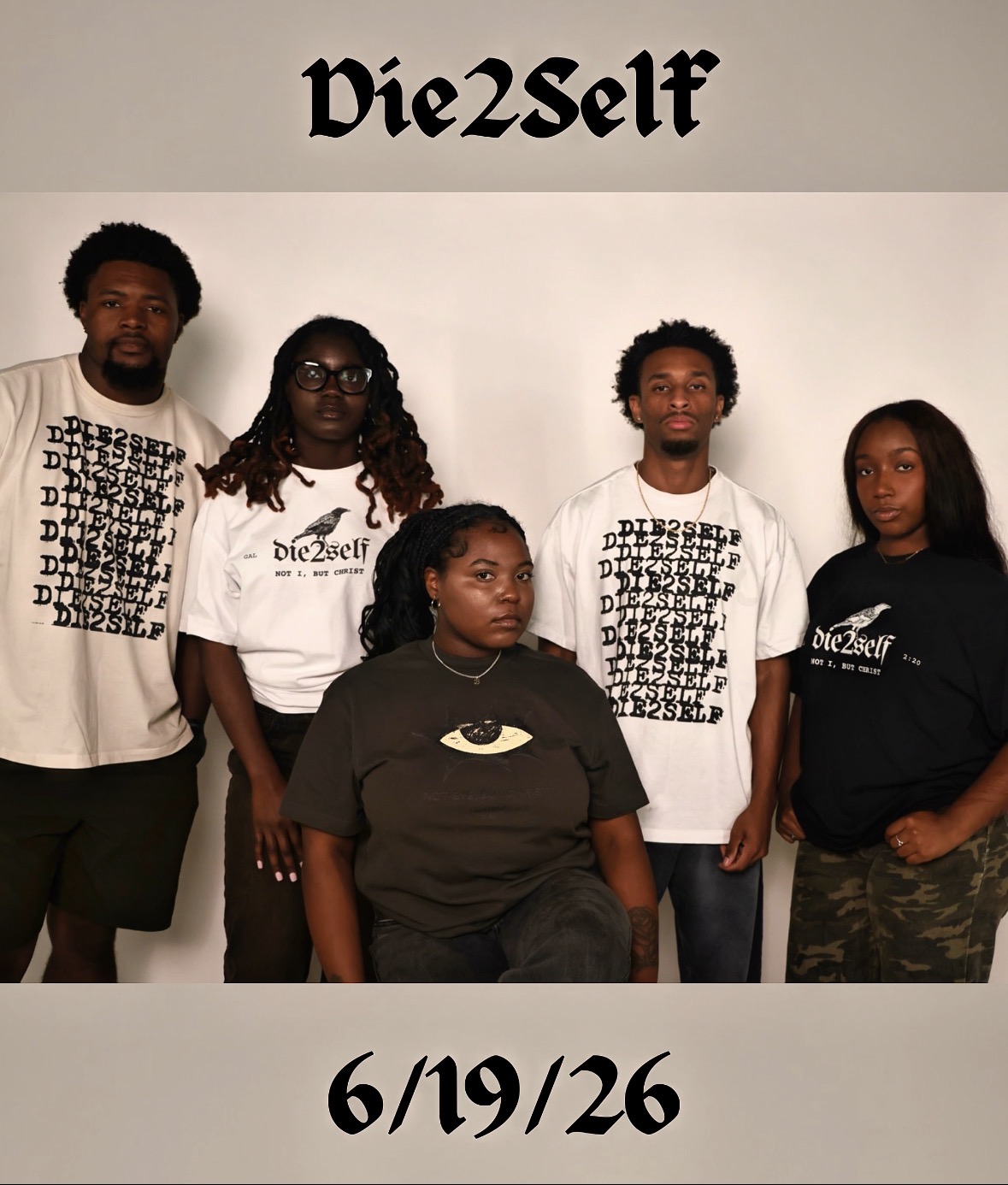 Group of five people standing in front of a wall with text, some wearing graphic t-shirts, one in camouflage pants.