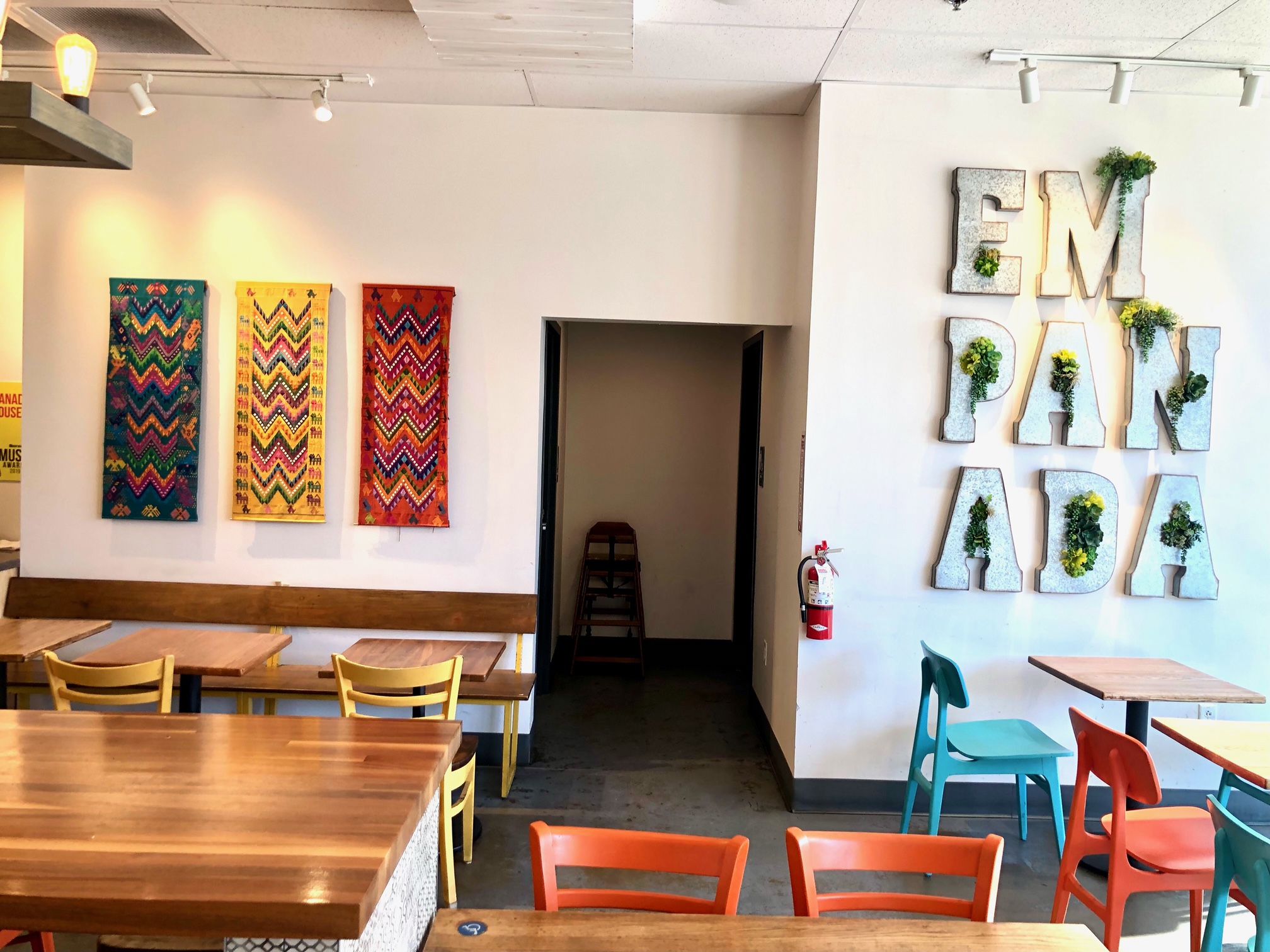 Interior of a cafe with colorful wall art, tables, and chairs, and decorative letters on the wall spelling 'EMPATHY'.