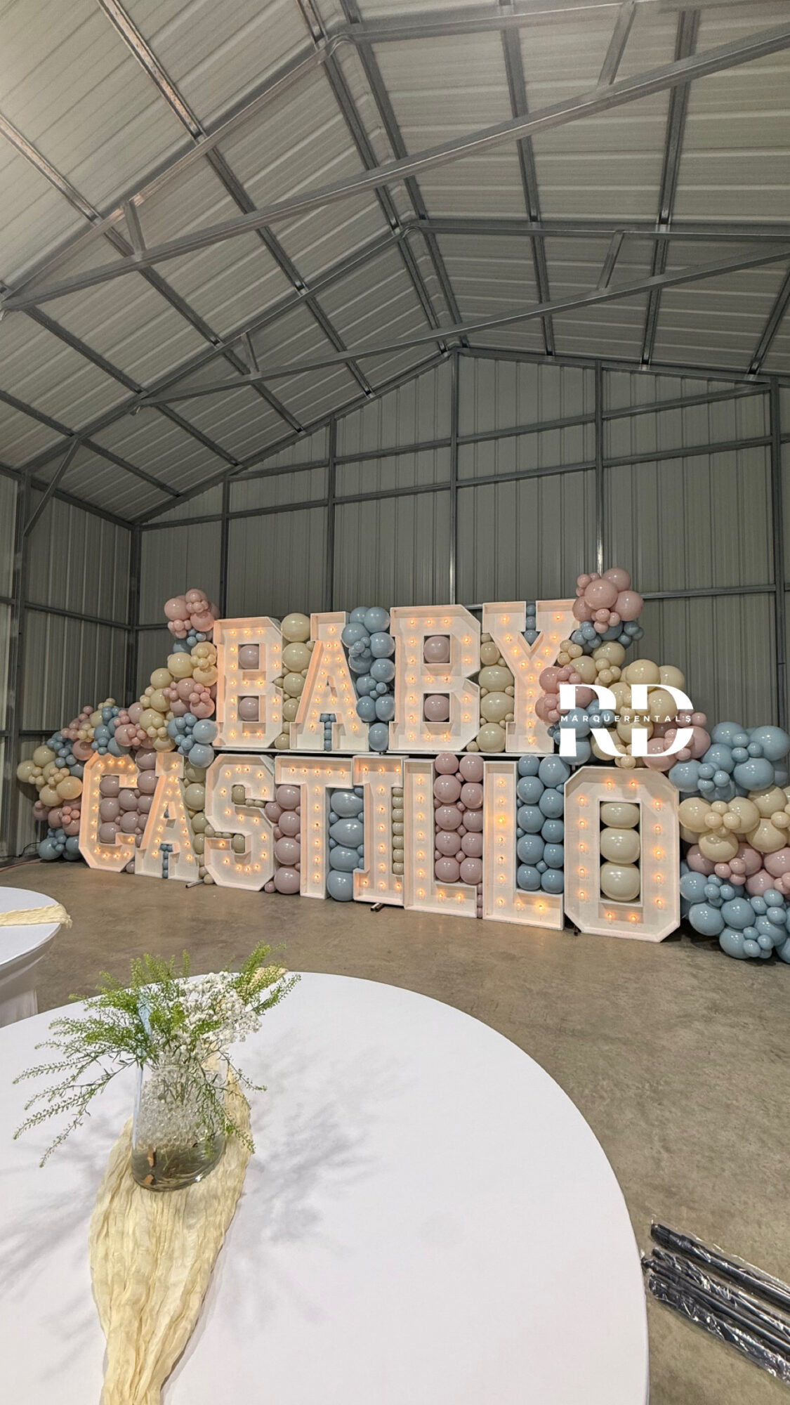 Decorative display with large letters spelling 'BABY' and 'CASTLE' surrounded by pastel balloons inside a metal building.
