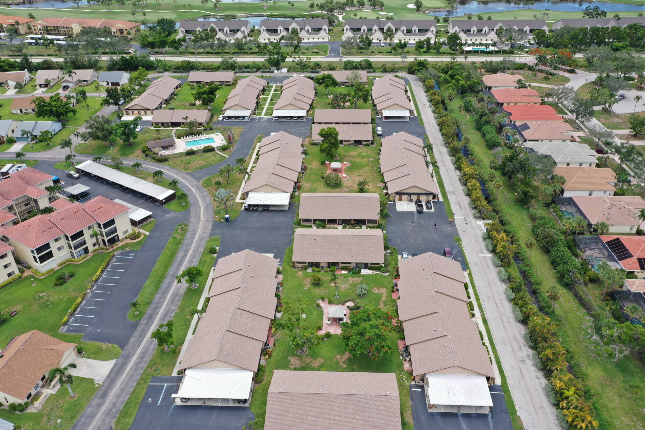 Aerial view of a residential area with multiple townhouses, green lawns, and parking lots, arranged in a grid pattern.