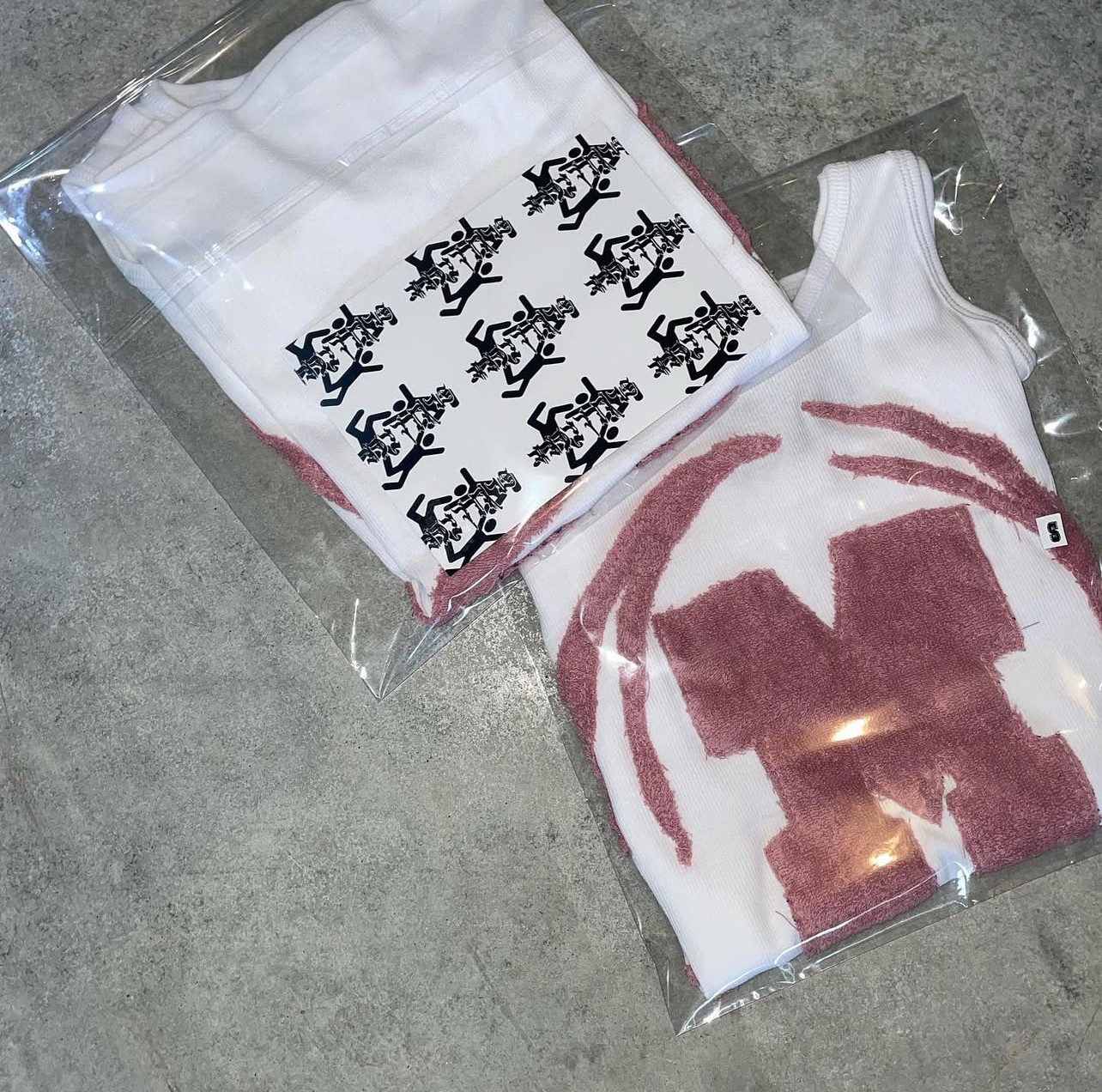 Two plastic bags containing clothing items, one with black and white animal illustrations and the other with a red and white design, on a gray surface.
