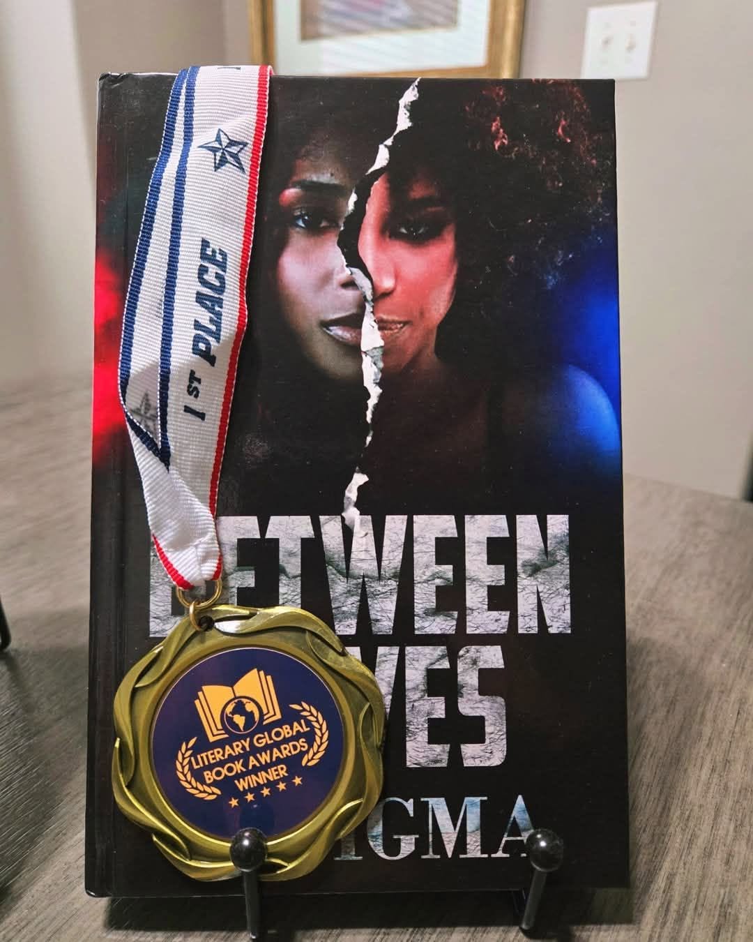 Book cover with a torn face split between two women, title partially visible, medal with blue and gold design in front.