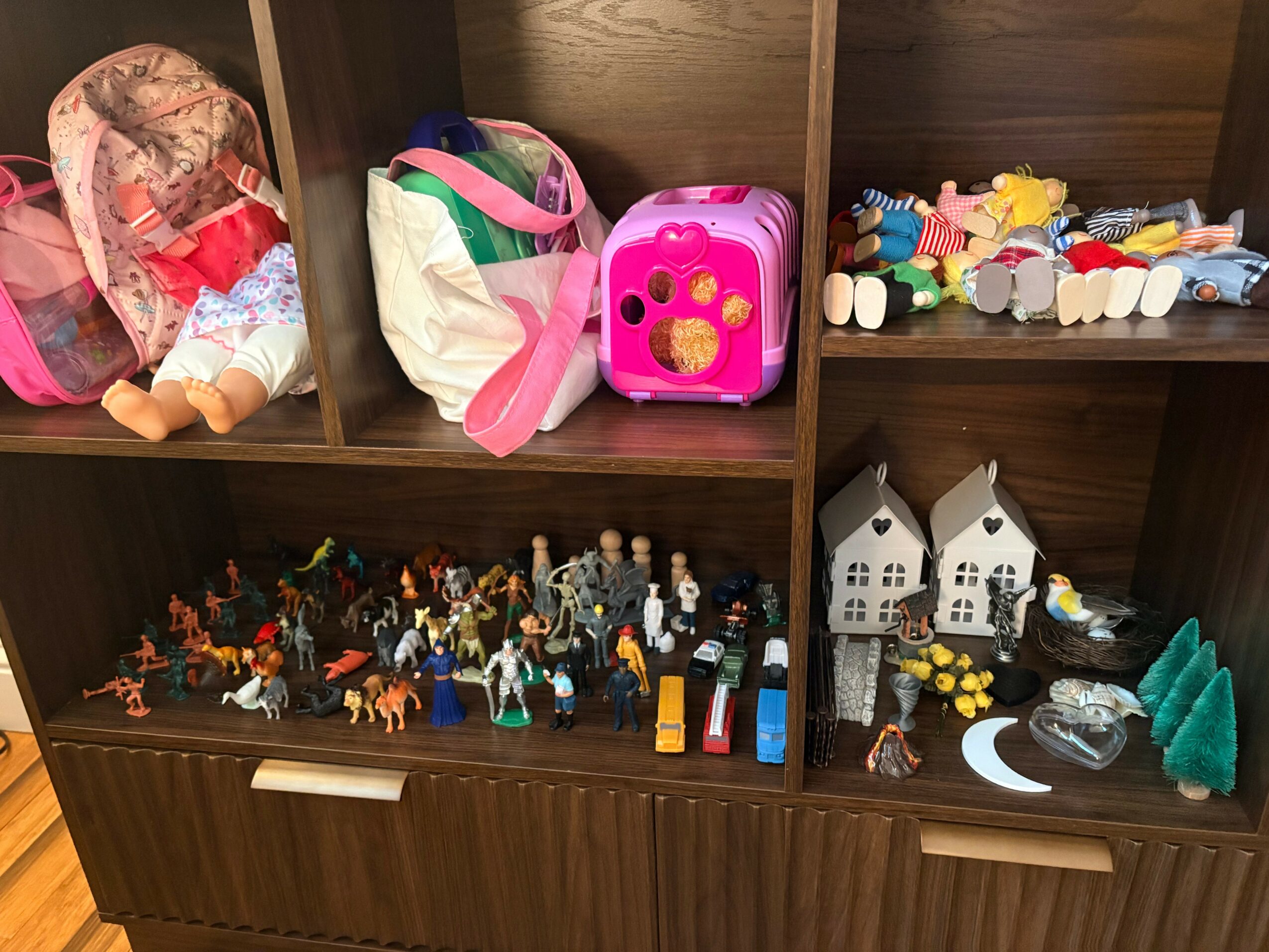 Shelves filled with toys, including dolls, miniature figures, toy houses, and colorful blocks.