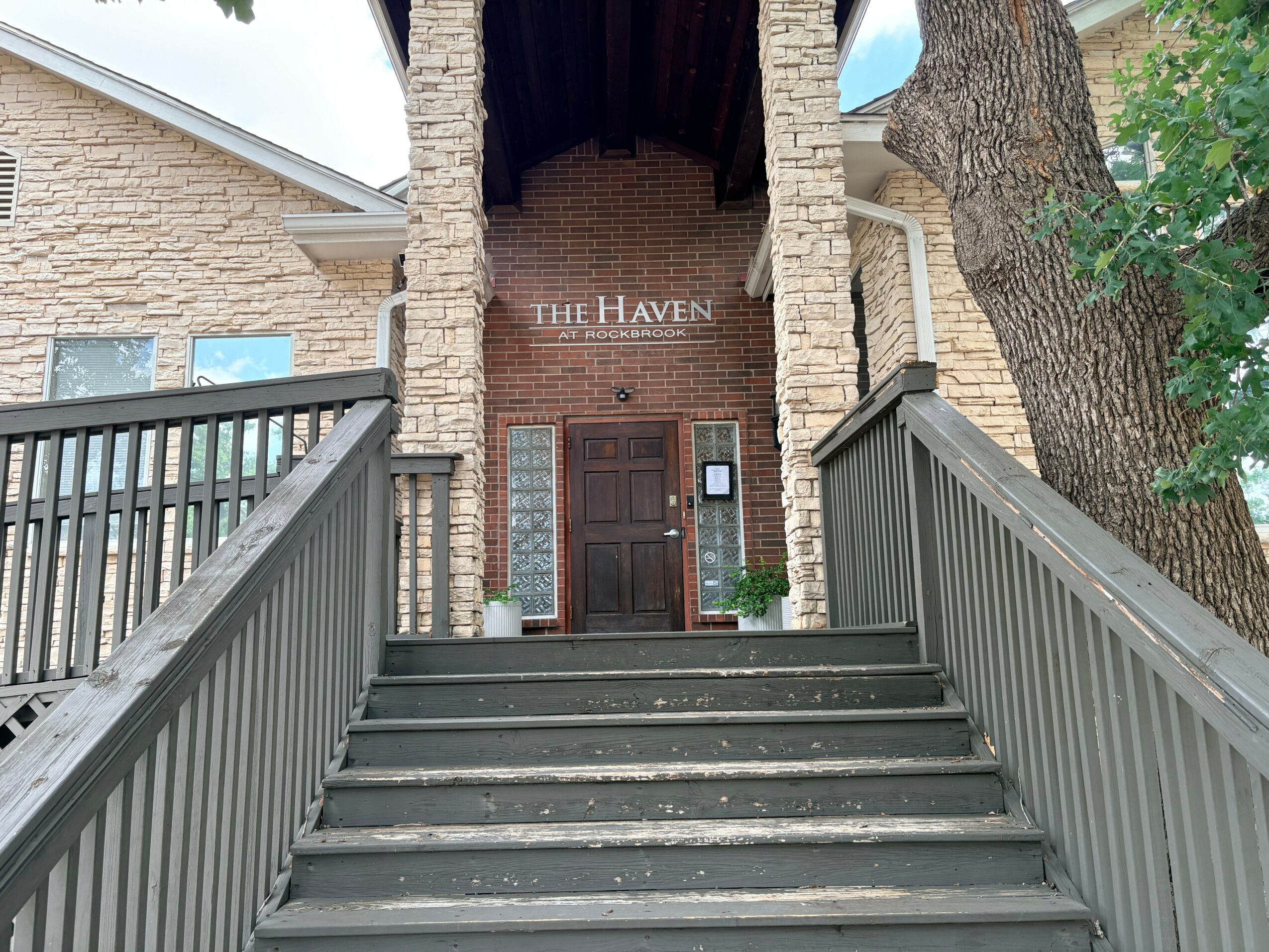 Front entrance with stairs, railing, brick walls, and a sign reading 'The Haven' above the door.