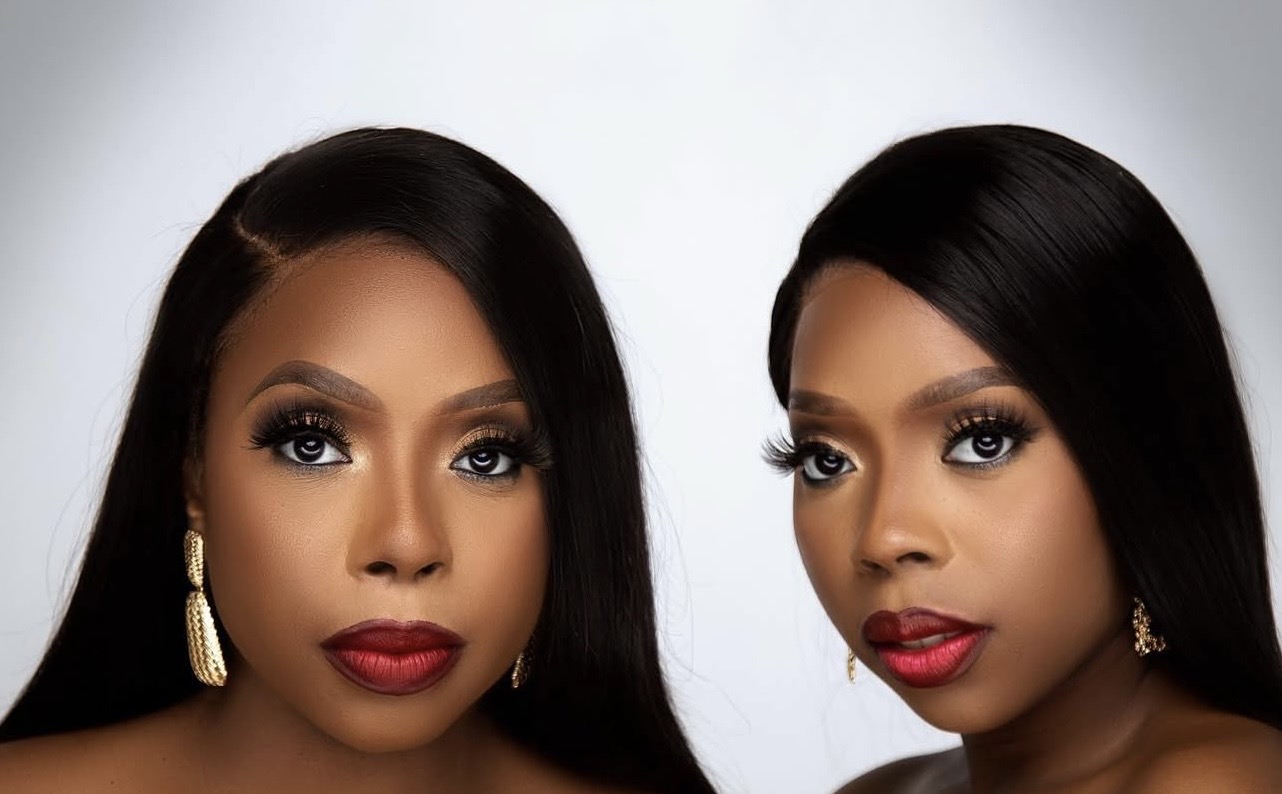 Two women with long black hair, makeup, and earrings, facing forward against a light background.
