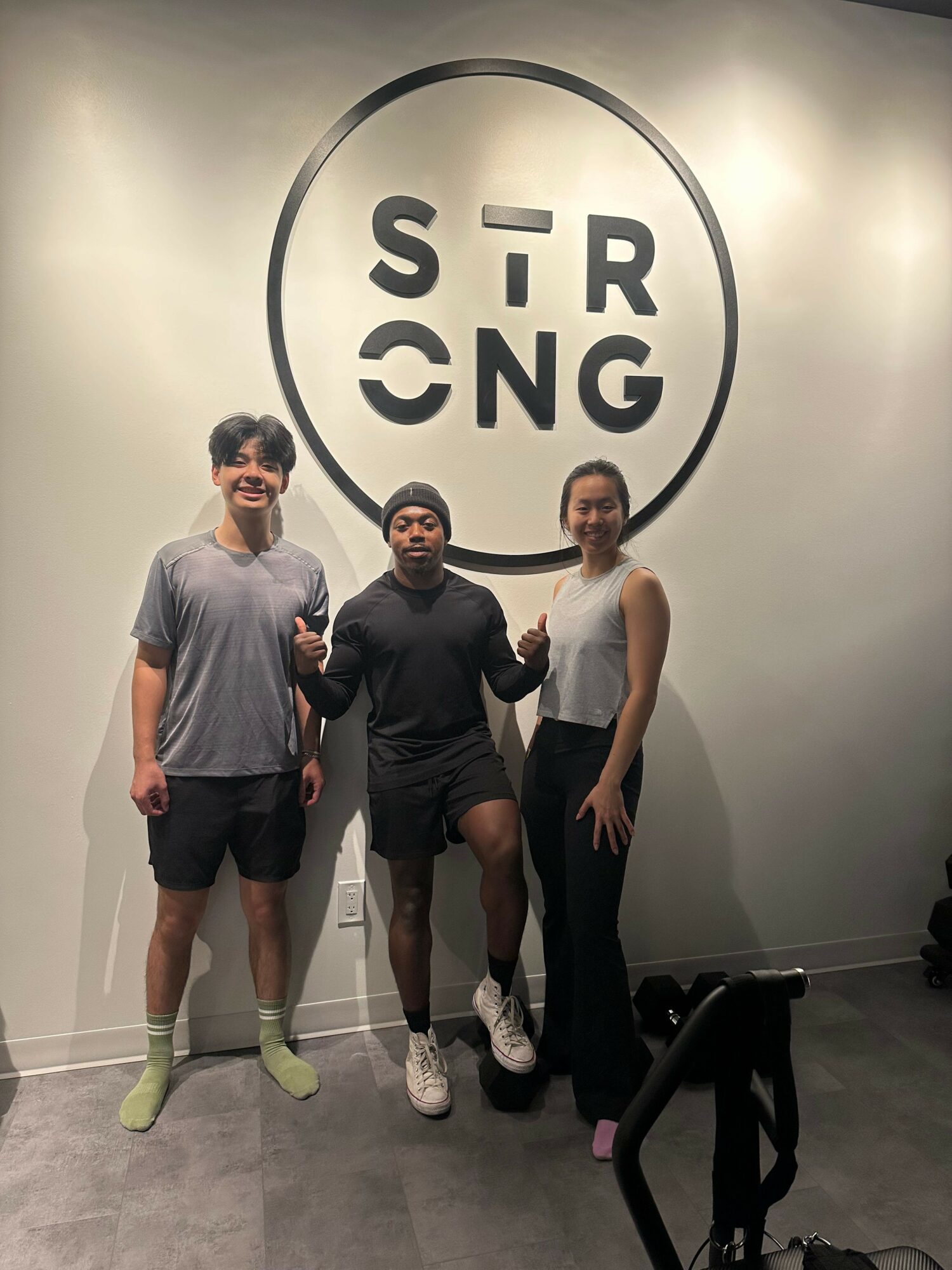 Three people standing in front of a wall with a circular logo reading 'SIR CNG'.