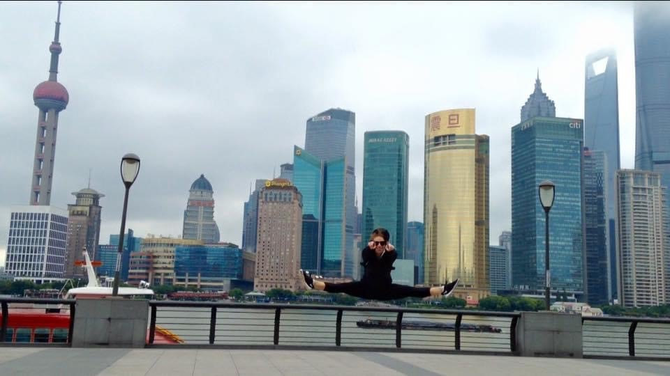 Person standing on a bridge with a city skyline and tall buildings in the background under cloudy sky.