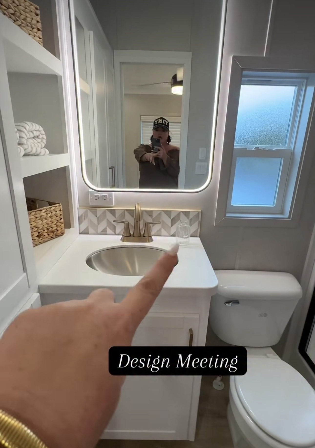 Person's finger pointing at bathroom sink with mirror and window, labeled 'Design Meeting'.