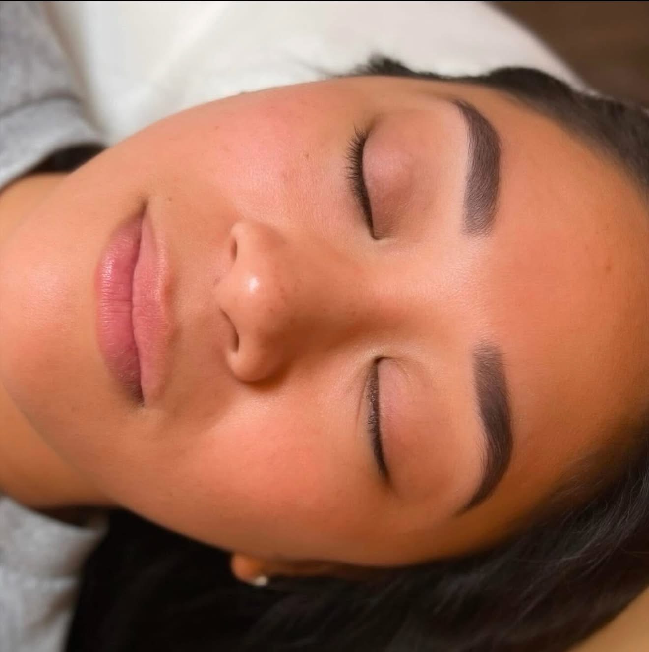 Close-up of a woman's face with eyes closed, showing smooth skin and well-groomed eyebrows.