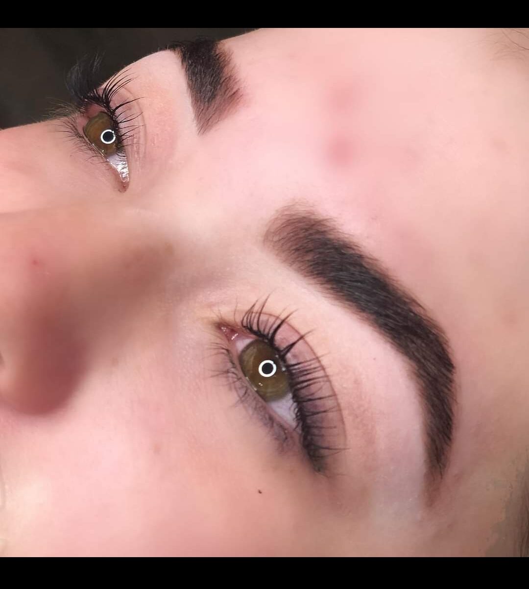 Close-up of a person's eyes with well-groomed eyebrows and long eyelashes, looking to the side.