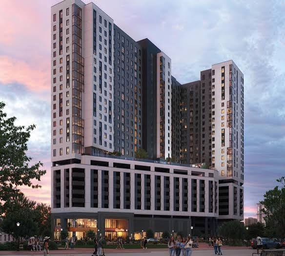 Modern multi-story building with a mixed-use design, featuring a lower commercial area and upper residential or office spaces, at dusk.