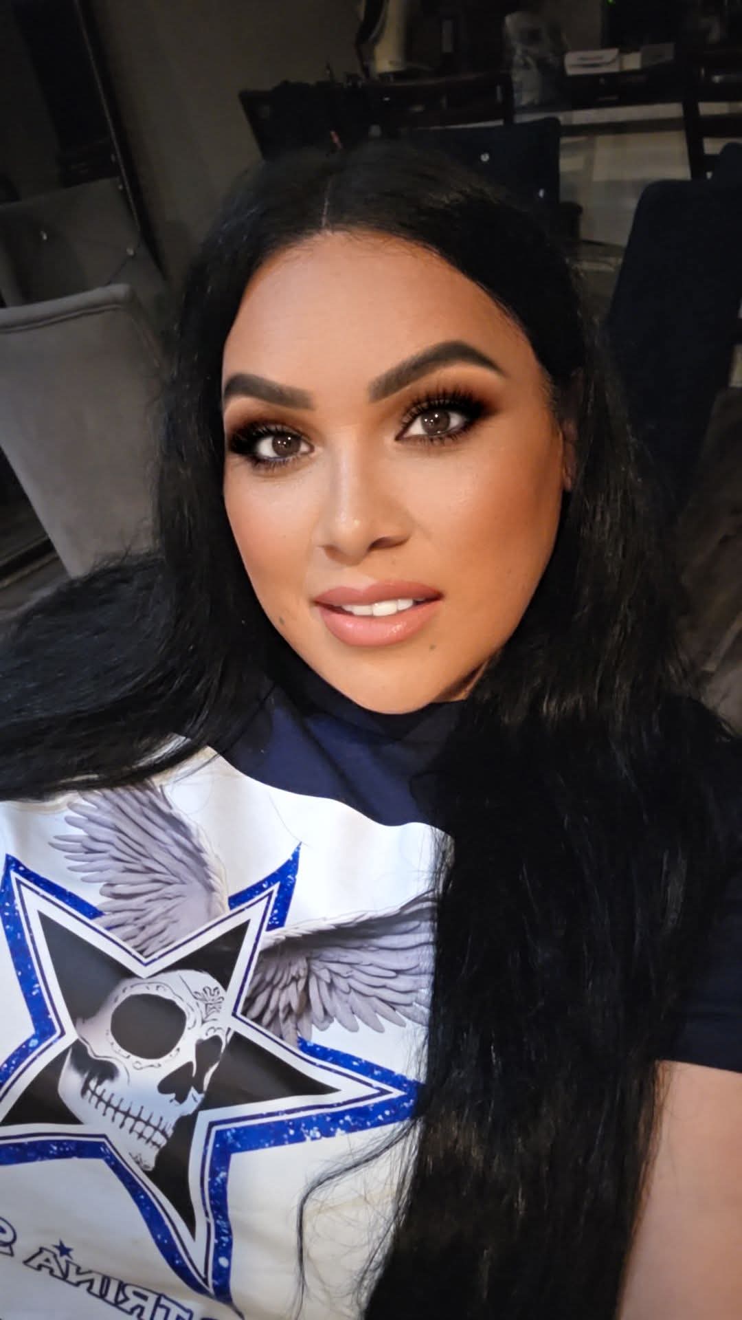 Close-up of a woman with long dark hair, makeup, and a graphic T-shirt featuring a skull and star design.