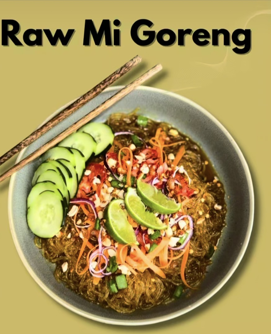 Bowl of raw instant noodles with cucumber slices, lime wedges, and vegetables, with chopsticks on top.