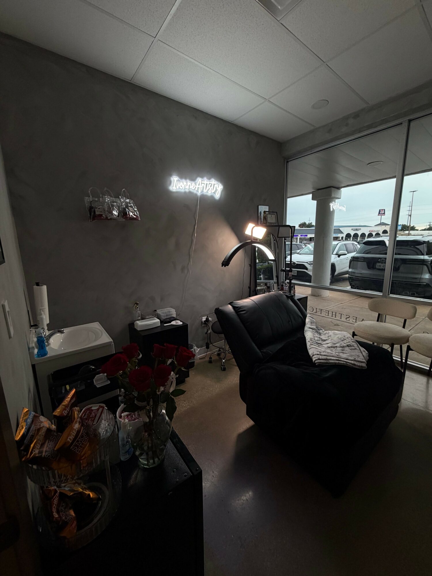 Office interior with desk, chair, and window showing parked cars outside.