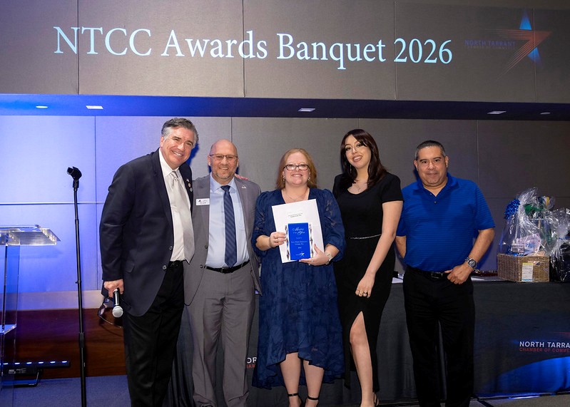 Group of five people standing on stage at NTCC Awards Banquet 2026, with a woman holding an award, background screen displaying event name.