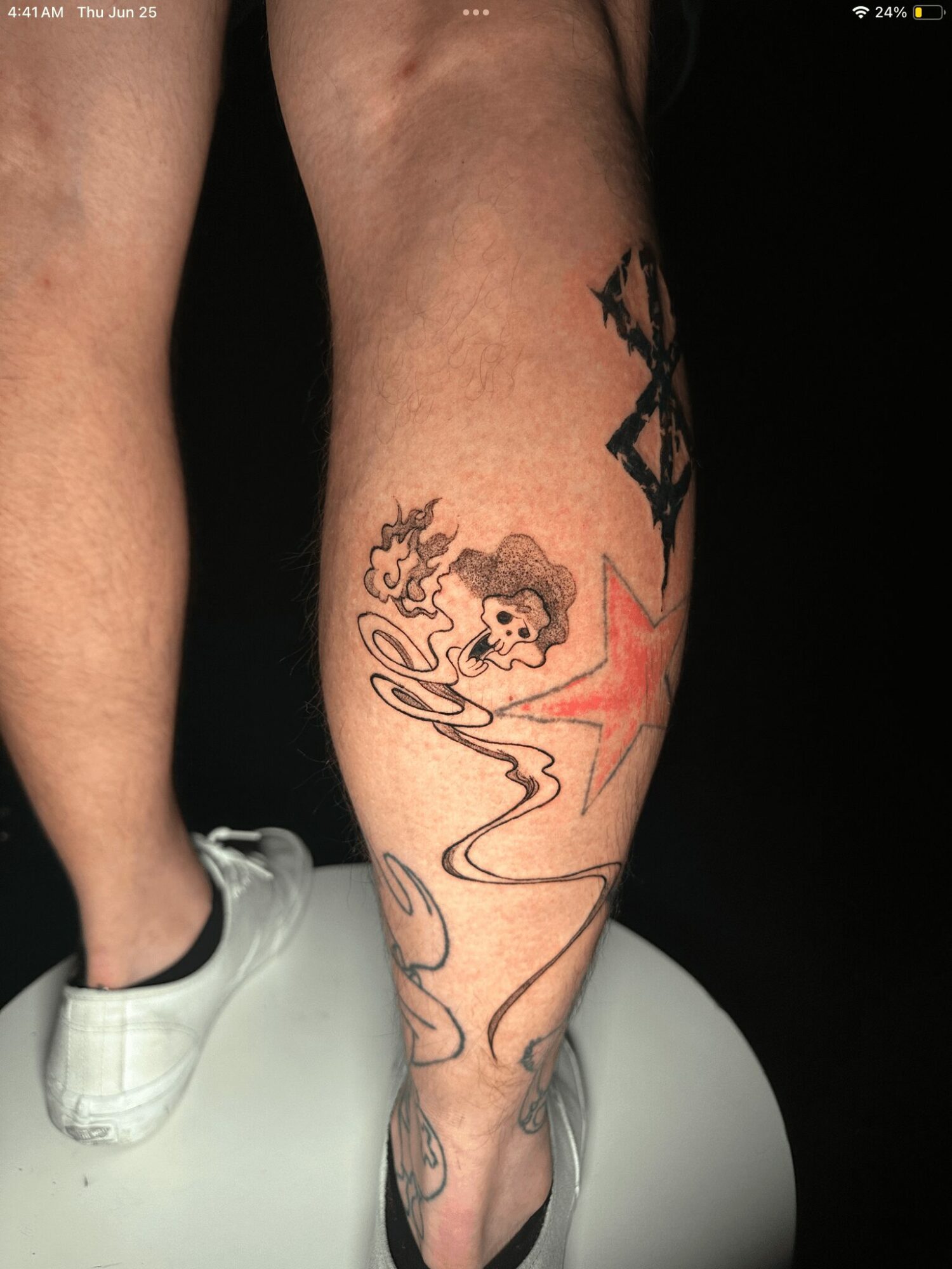 Tattoo of a woman with curly hair, smoking, with a star and abstract design on a person's calf.