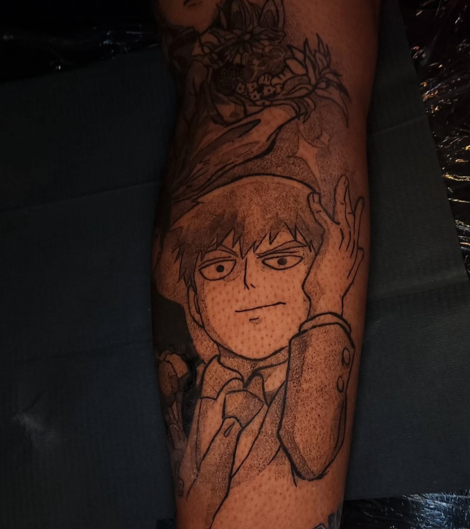Tattoo of a young person with glasses and a serious expression, holding their hand near their face, on a person's arm.