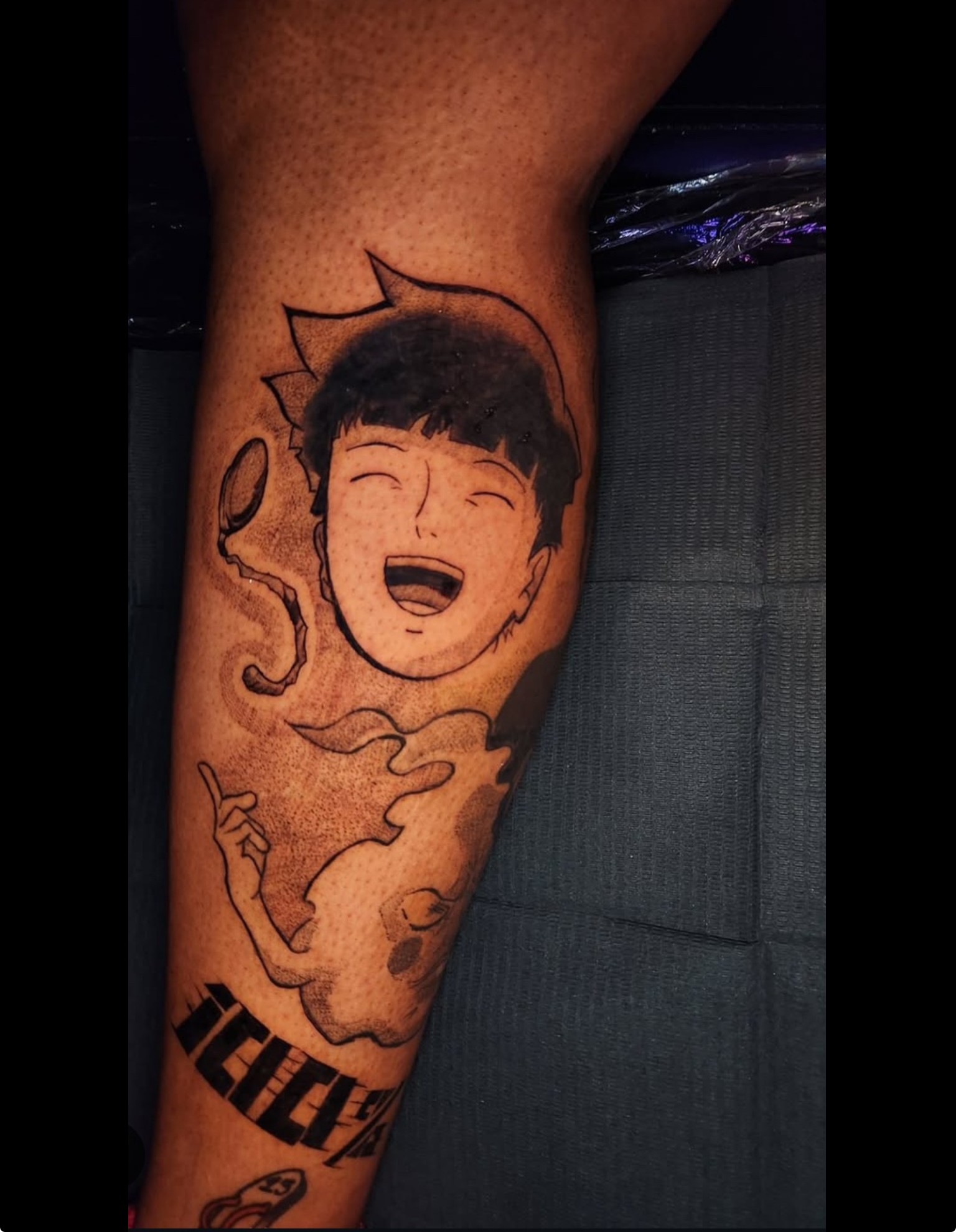 Tattoo of a smiling cartoon character with short hair, surrounded by smoke or clouds, on a person's arm.