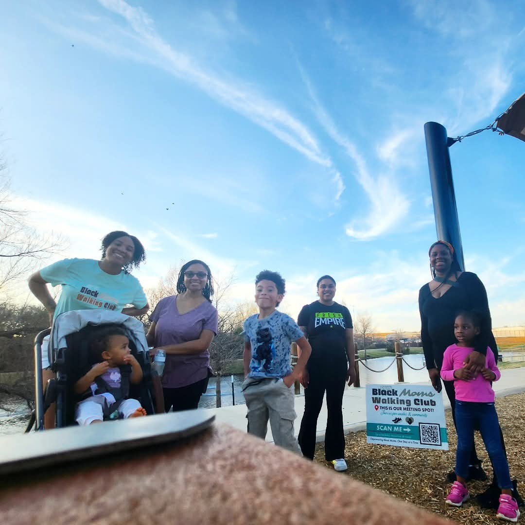 Group of six people, including children, standing outdoors near a basketball hoop on a sunny day.