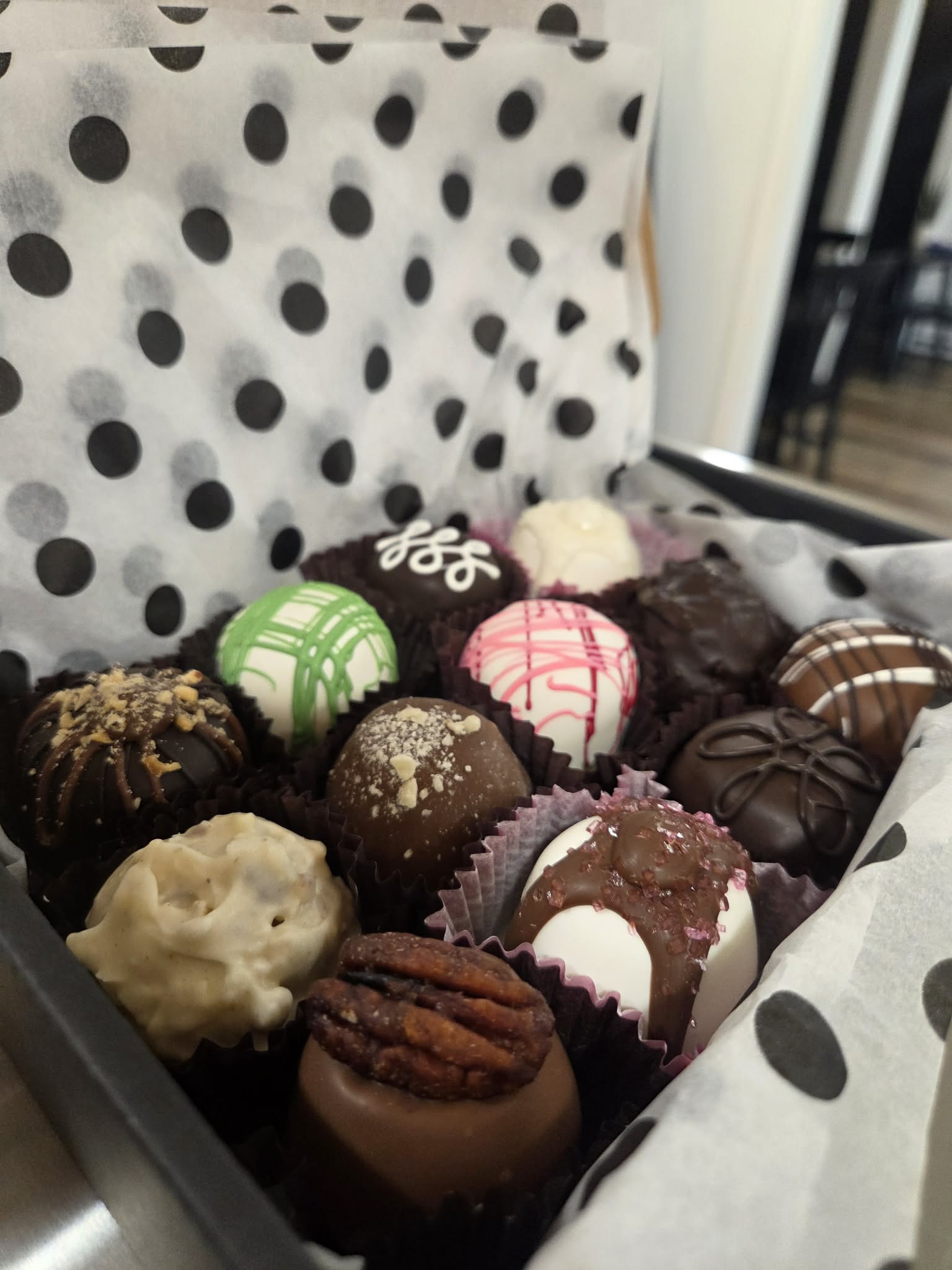 Assorted decorated chocolates and truffles in a box with polka dot paper lining.