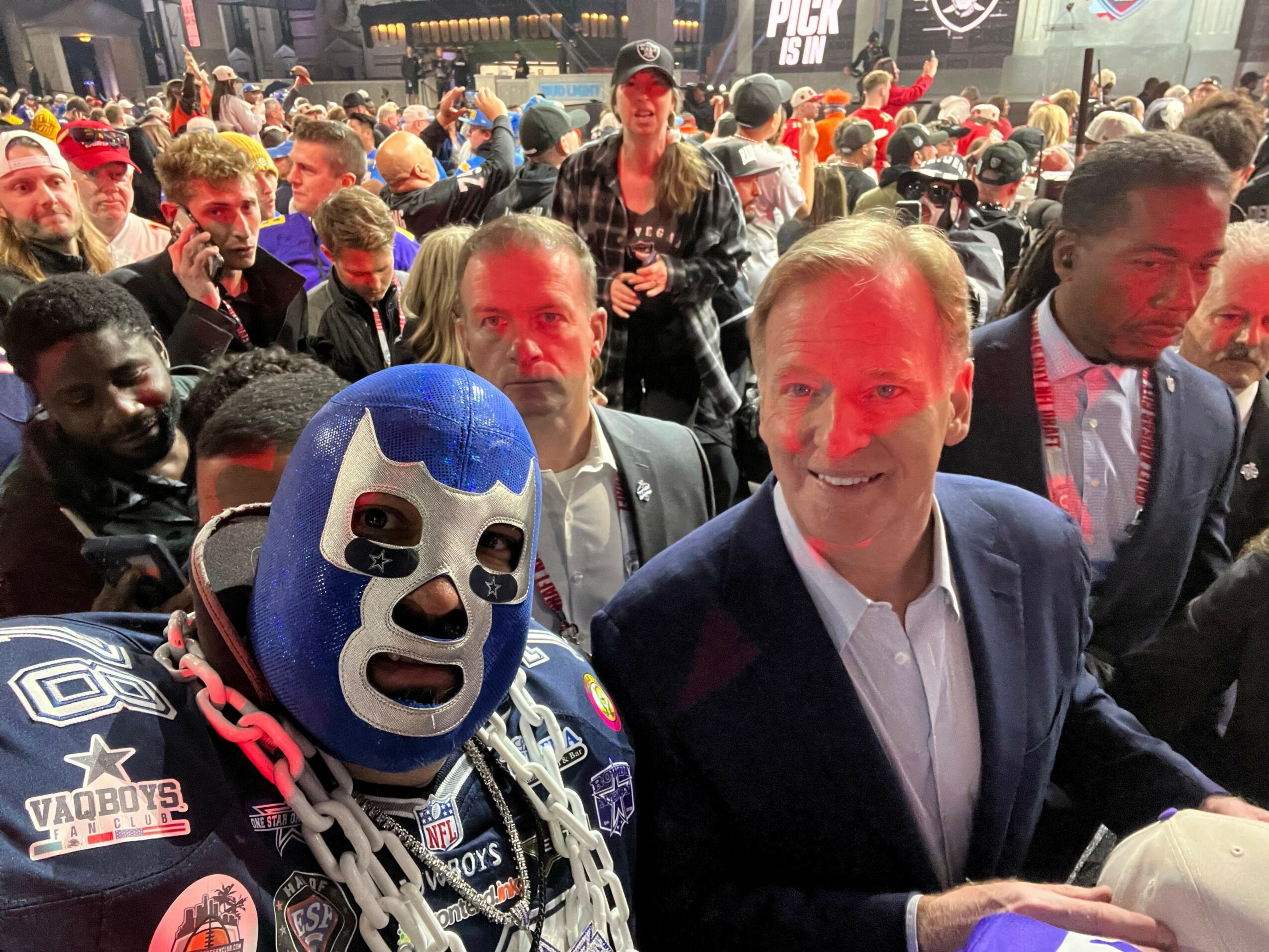 Crowd of people wearing masks and costumes at an event, with some holding chains and accessories.