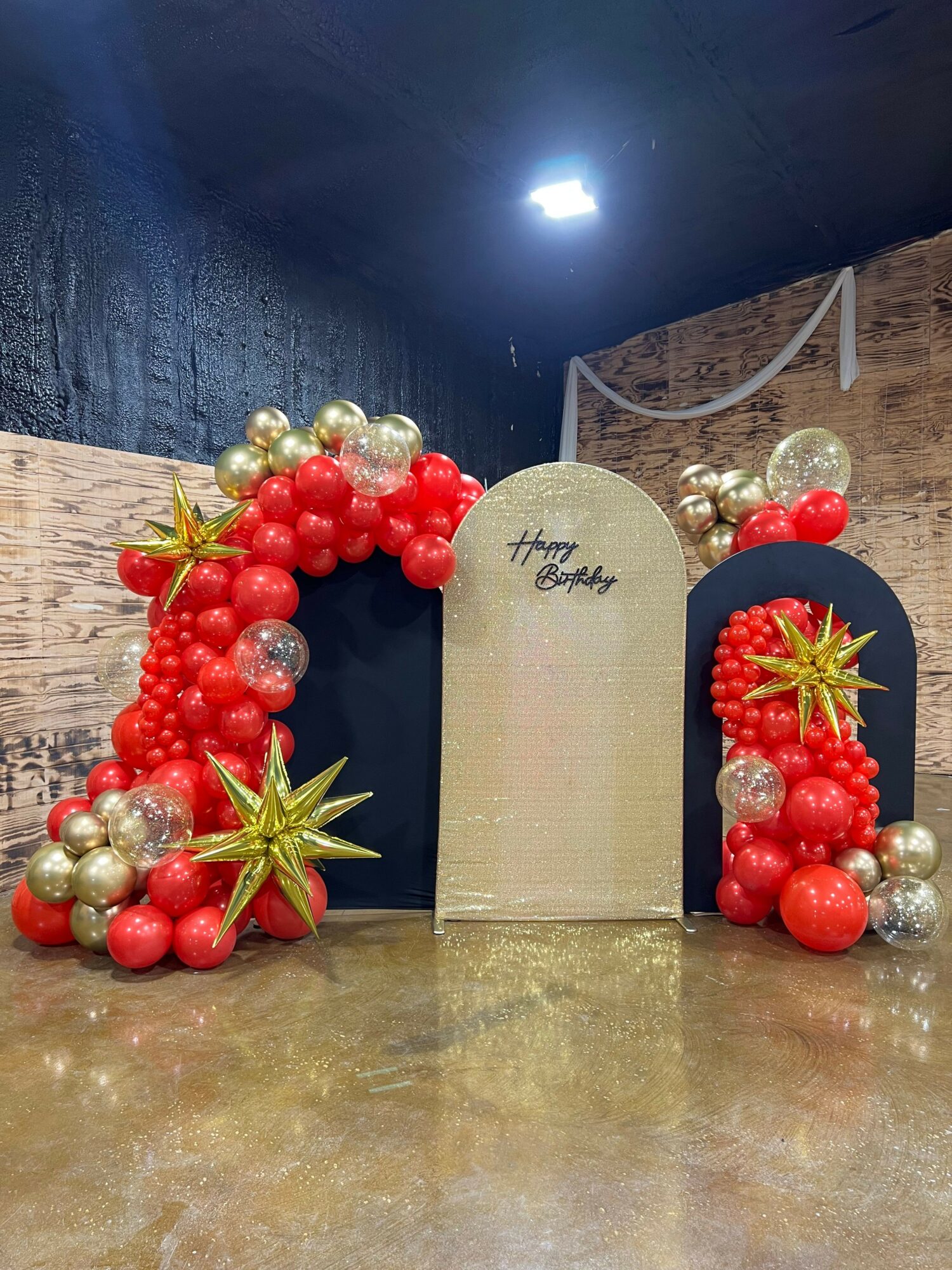 Decorative arrangement with red, gold, and silver ornaments, and a beige card with handwritten text, on a wooden surface.