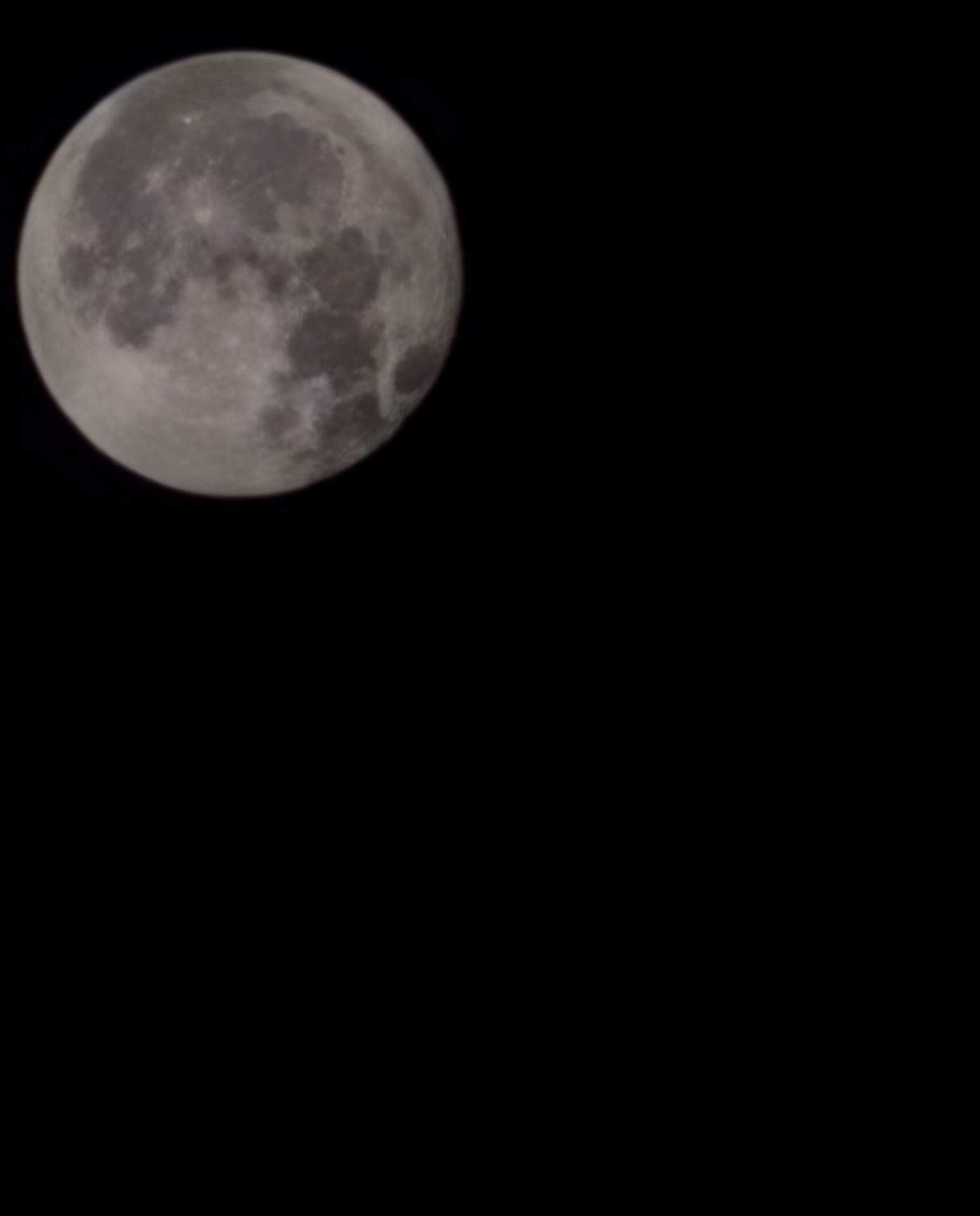 Full moon in a dark sky with some clouds, detailed surface visible.